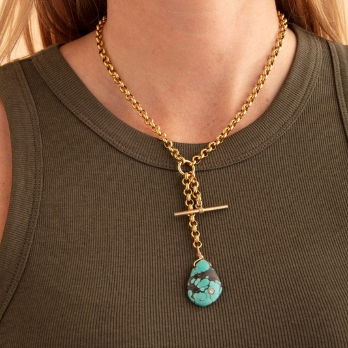 Woman in an olive ribbed tank wearing a gold rolo chain T-bar necklace with a turquoise teardrop pendant
