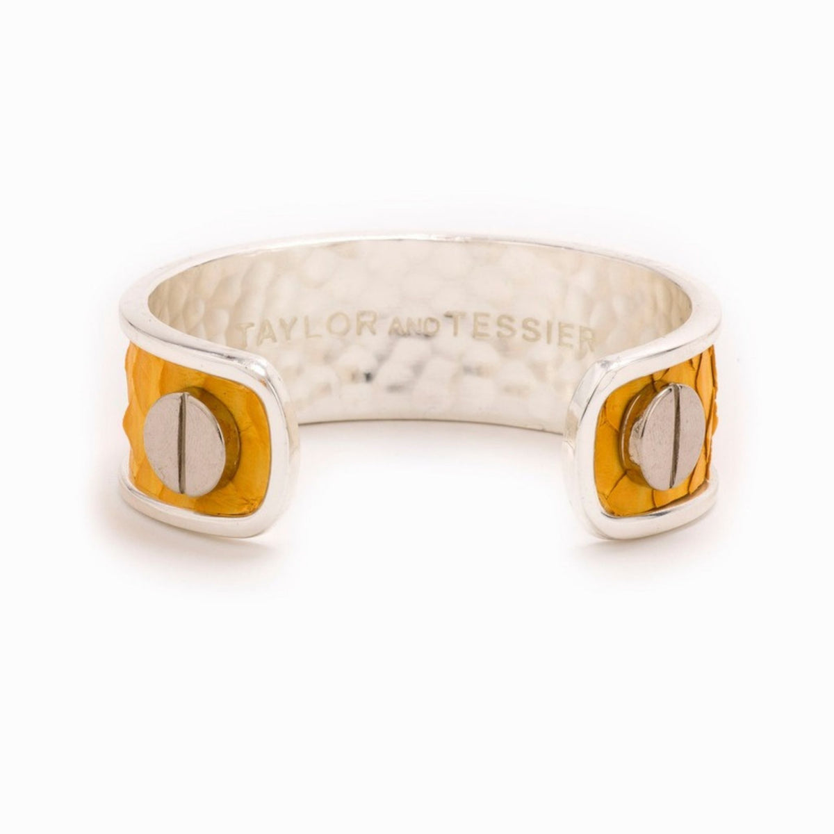 Inside view of a silver cuff with a mustard yellow leather panel, silver screw heads and engraved logo