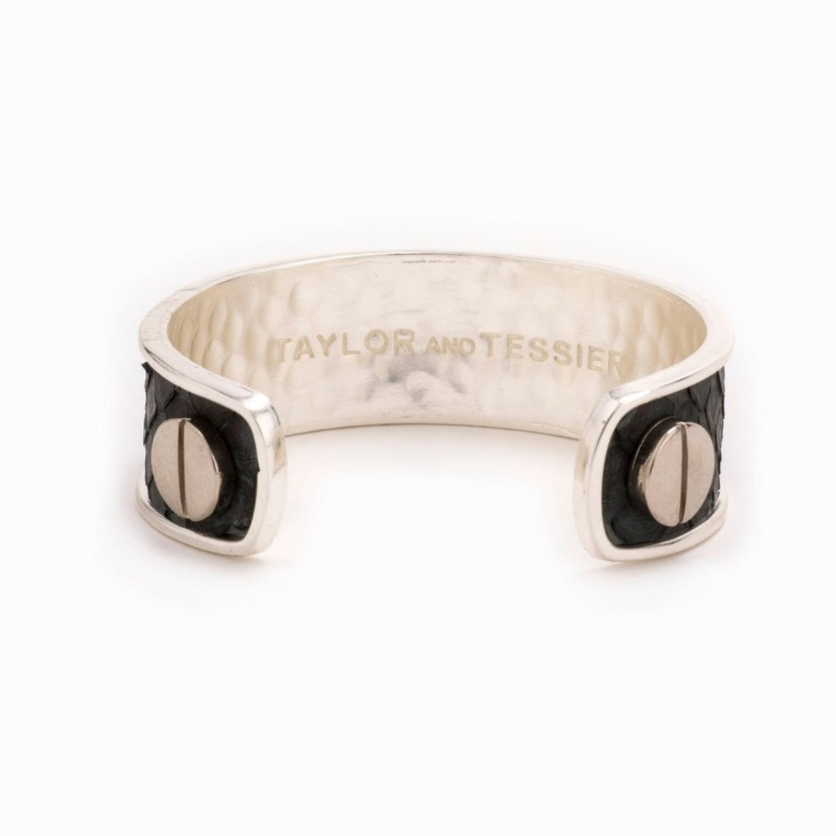 Inside view of a silver cuff with black leather ends, large silver screw heads and a hammered inner band