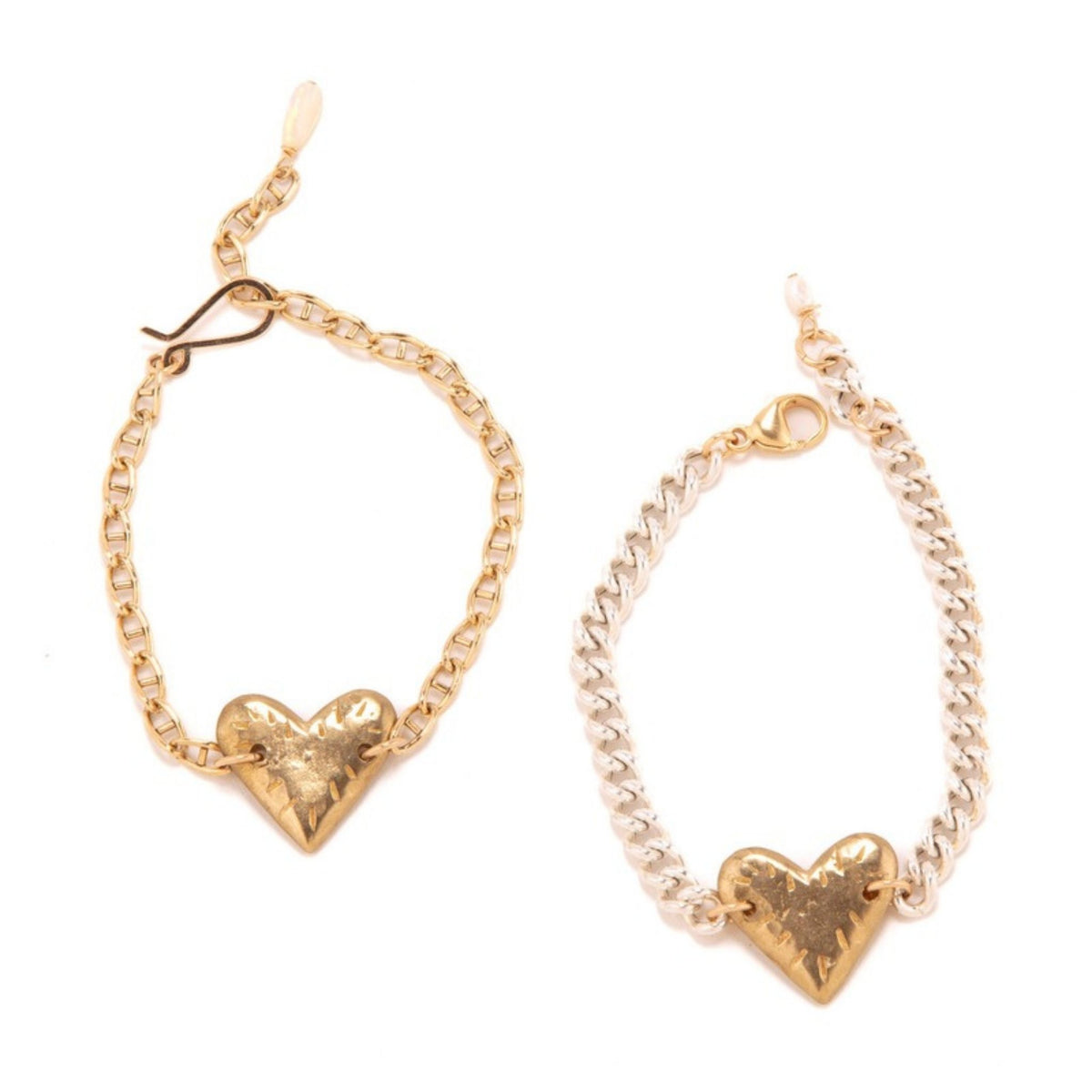 Two bracelets with hammered gold hearts, one on a gold anchor chain and one on a silver curb chain, on white
