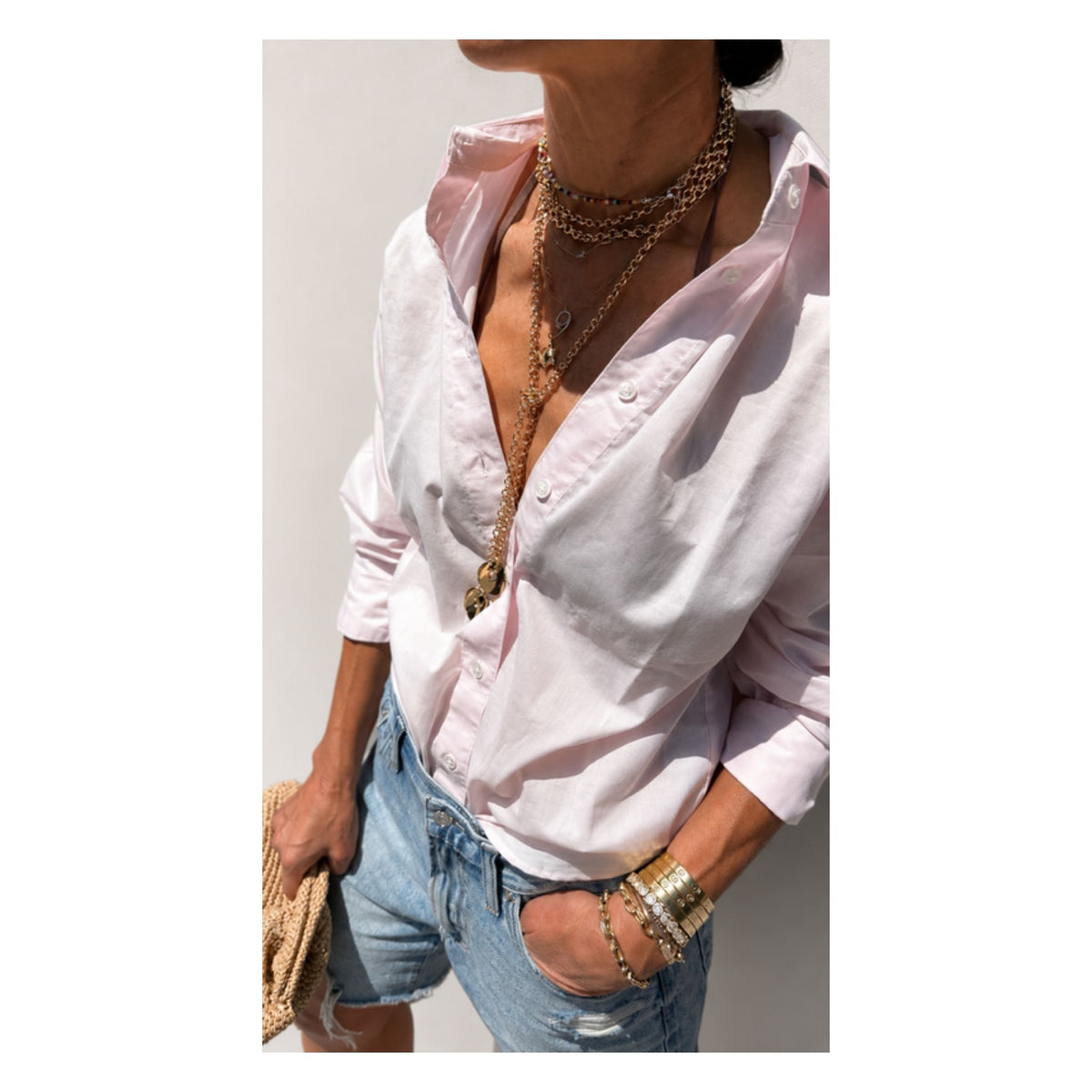 Sunny's Lariat Necklace by Taylor & Tessier, a long gold chain lariat with charms, worn open over a pale pink shirt