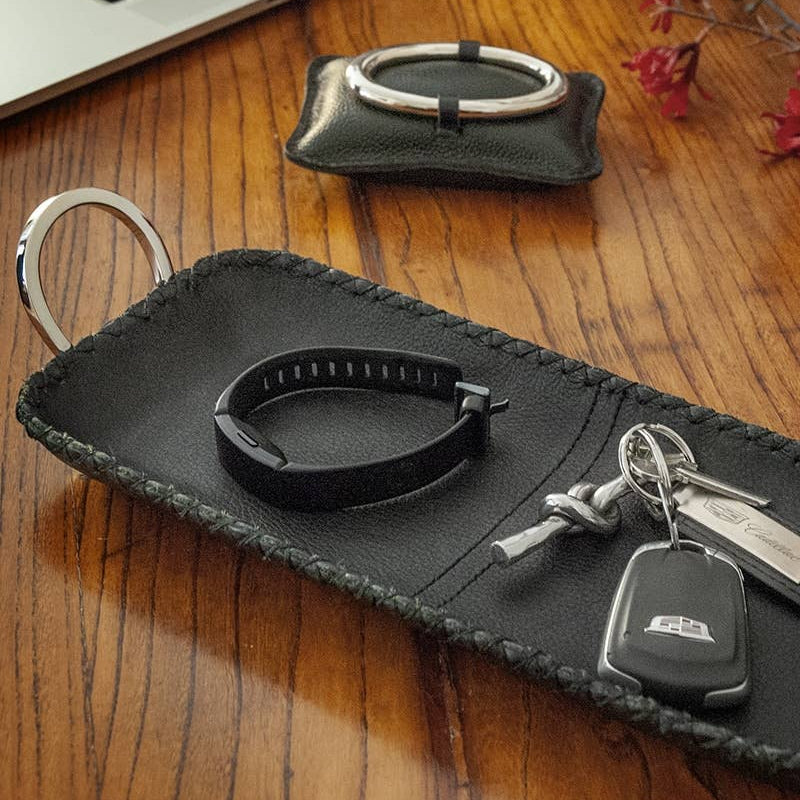 Black leather key holder with keys on a wooden surface