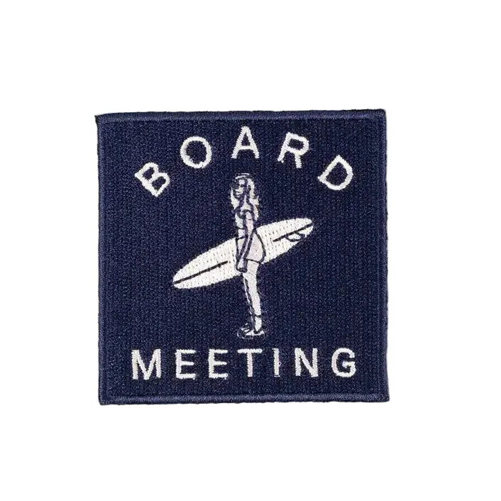 Embroidered iron on patch of a woman surfer with the text "Board Meeting" in white lettering, with a navy blue background.
