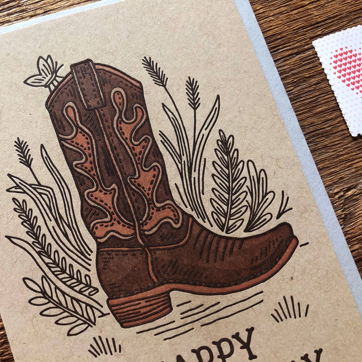 Card with a cowboy boot illustration on a wooden surface