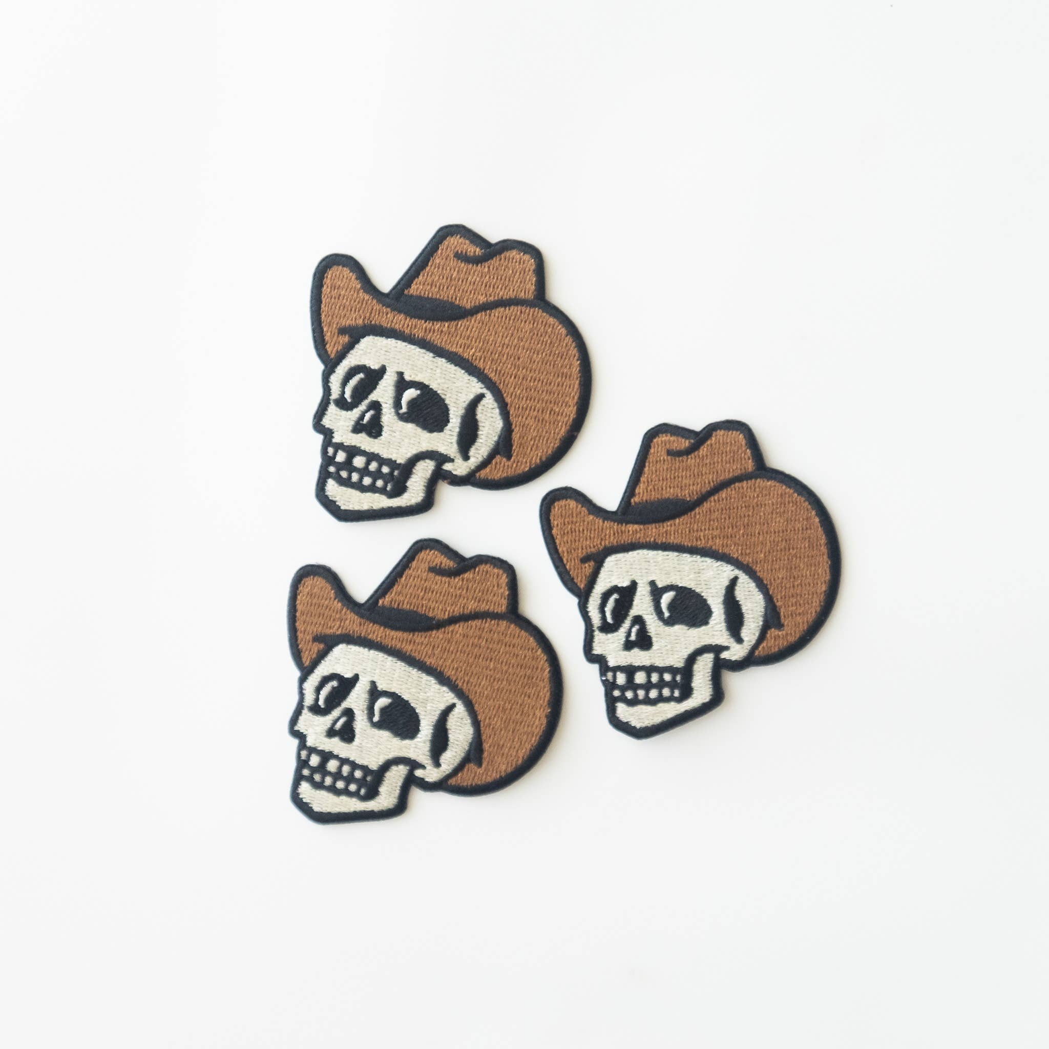 Three skull patches with cowboy hats on a white background.