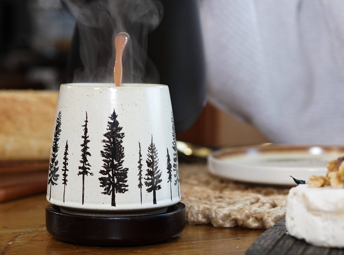 Ceramic Mug with tree designs on a wooden table.
