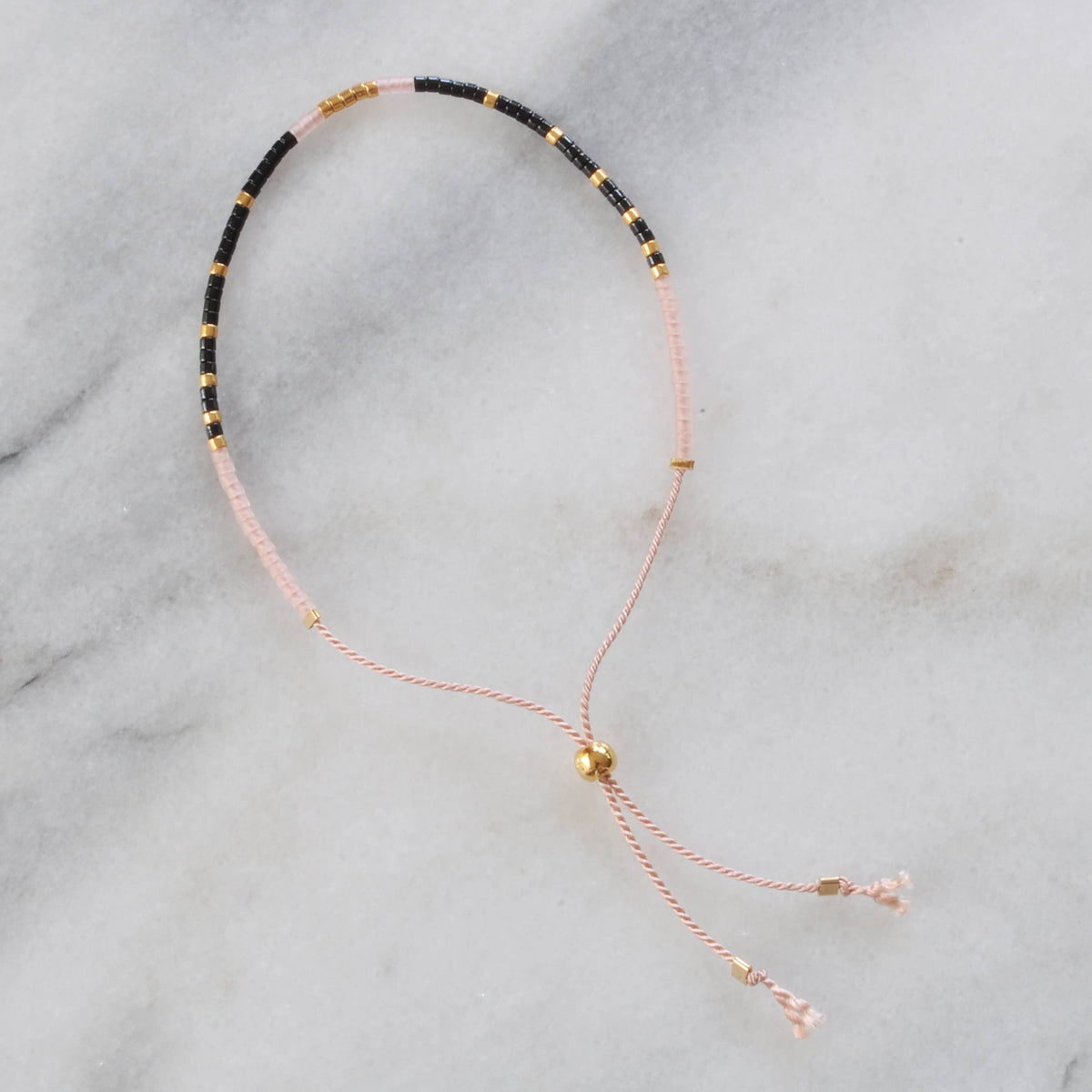 Beaded necklace with black, gold, and pink threads.