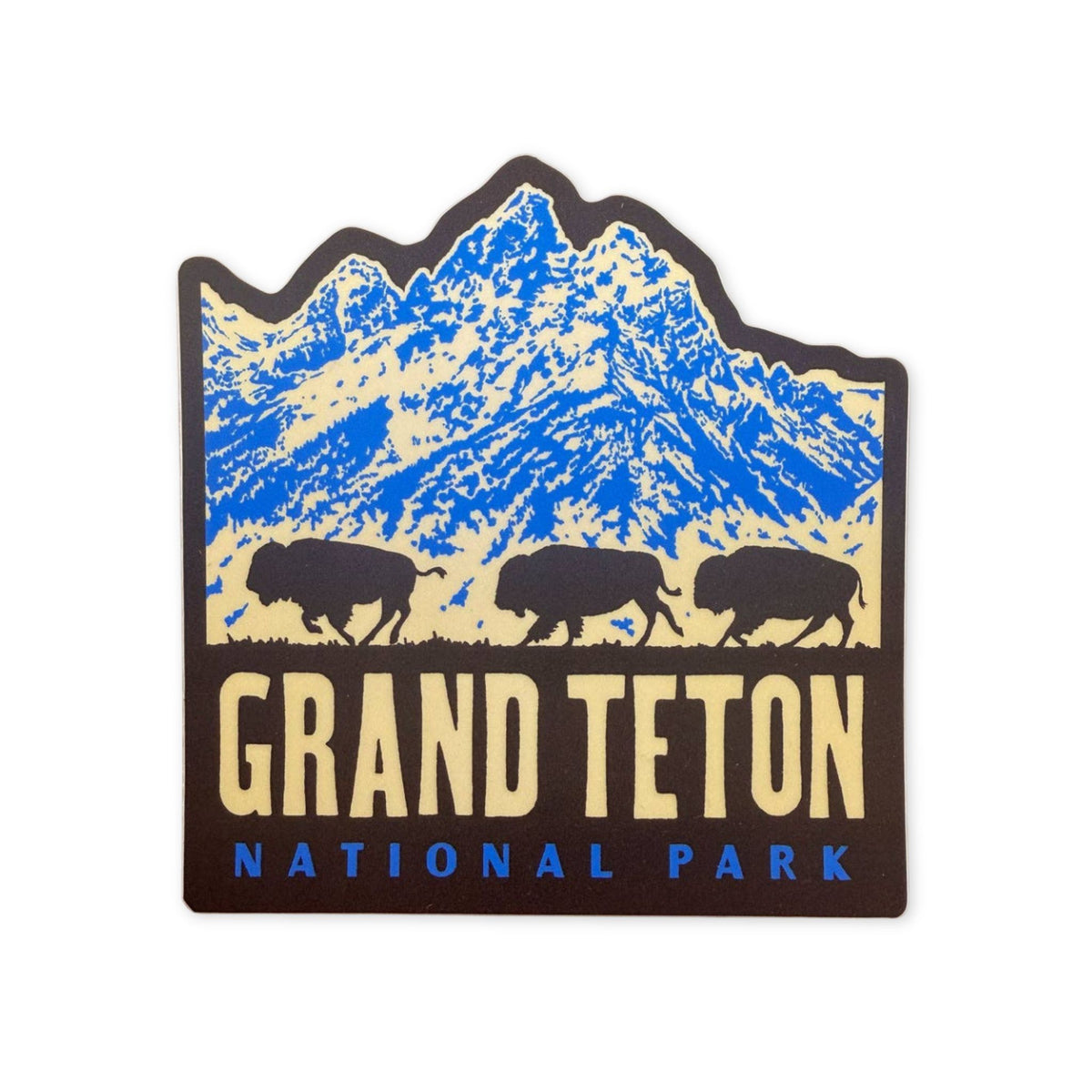 A die-cut sticker of Grand Teton National Park featuring blue and beige mountains, three black bison silhouettes, and the text 'GRAND TETON NATIONAL PARK'.