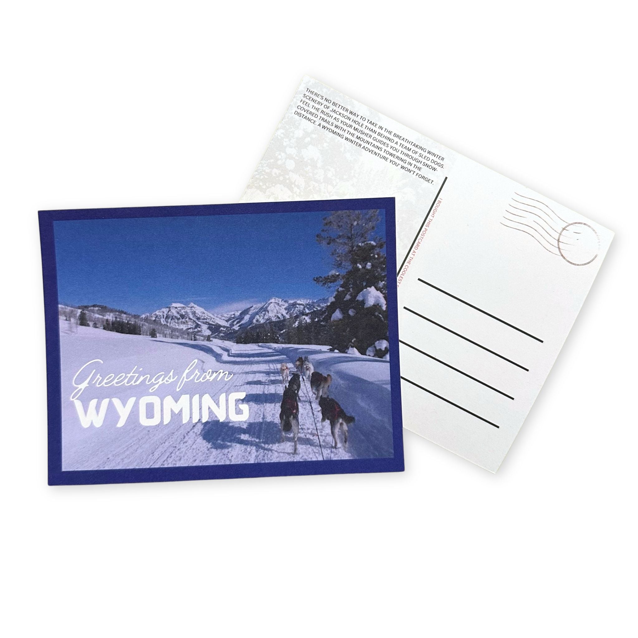 Postcard with snowy landscape and 'Greetings from Wyoming' text, featuring a dog sled.
