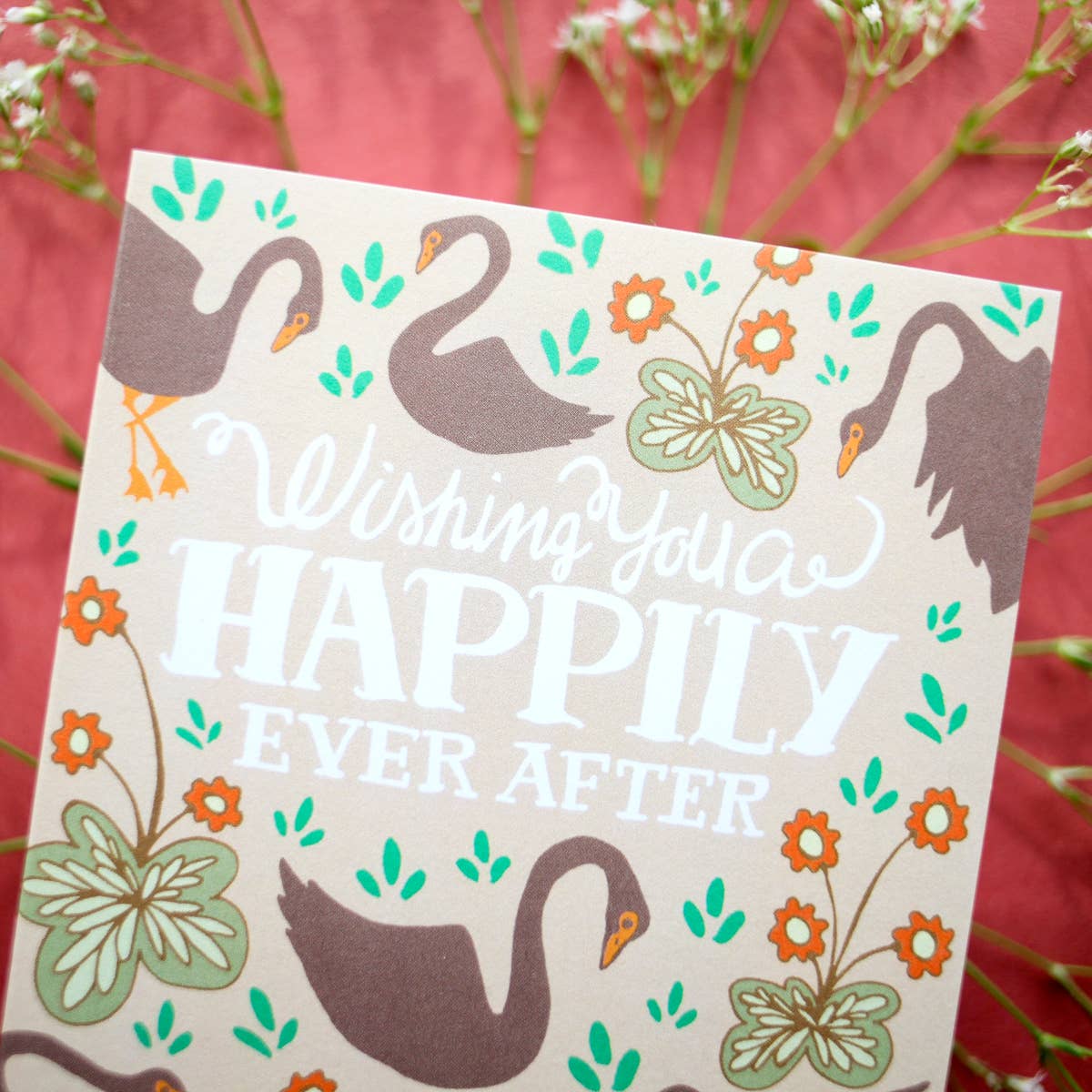 Card with swan design and text 'Wishing you a happily ever after' on a floral background.
