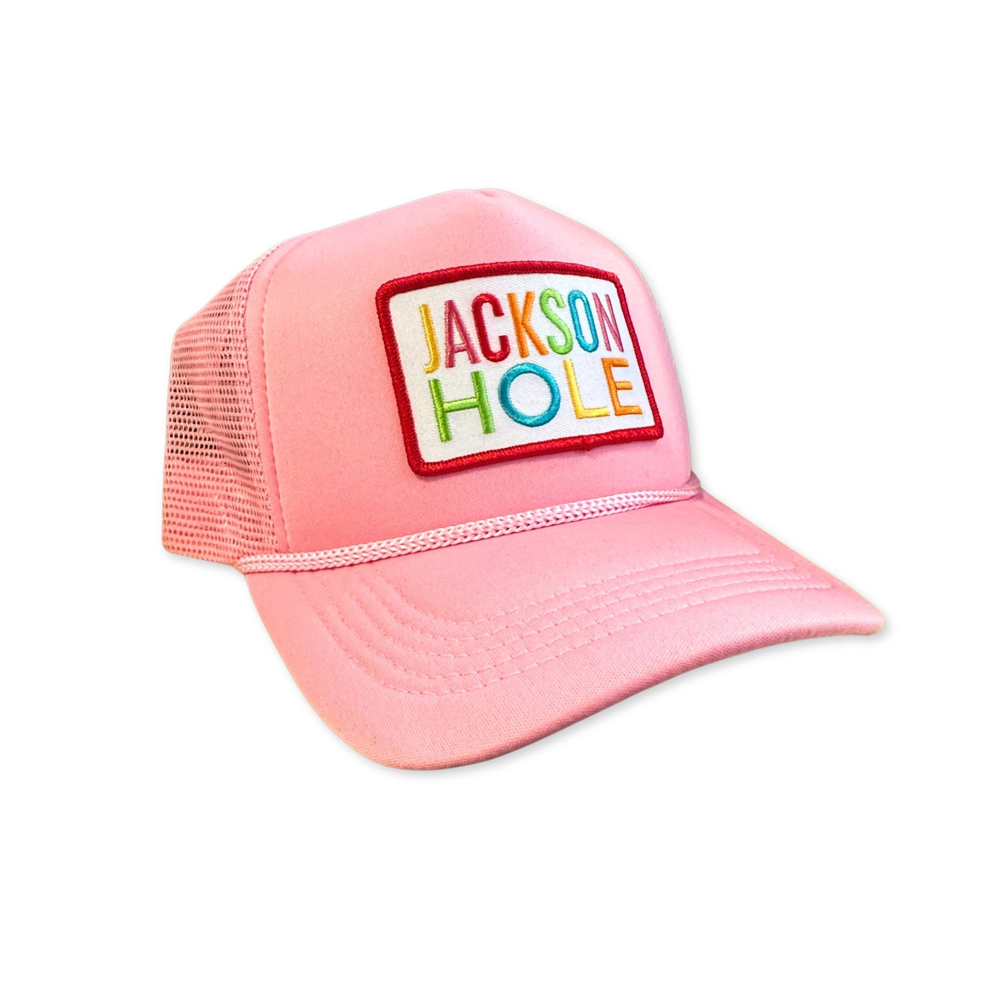 Pink trucker hat with 'Jackson Hole' Rainbow patch on a white background