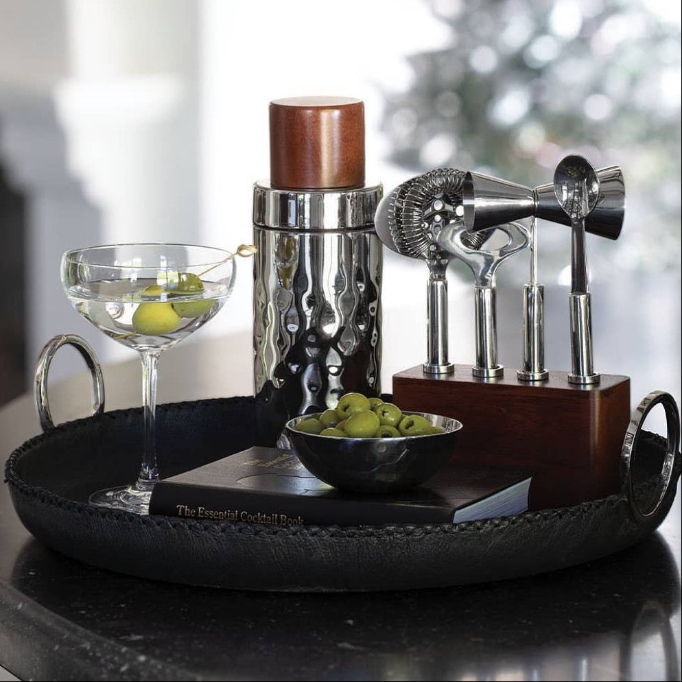 Bartending set with shaker, strainers, and cocktail glass on a tray.