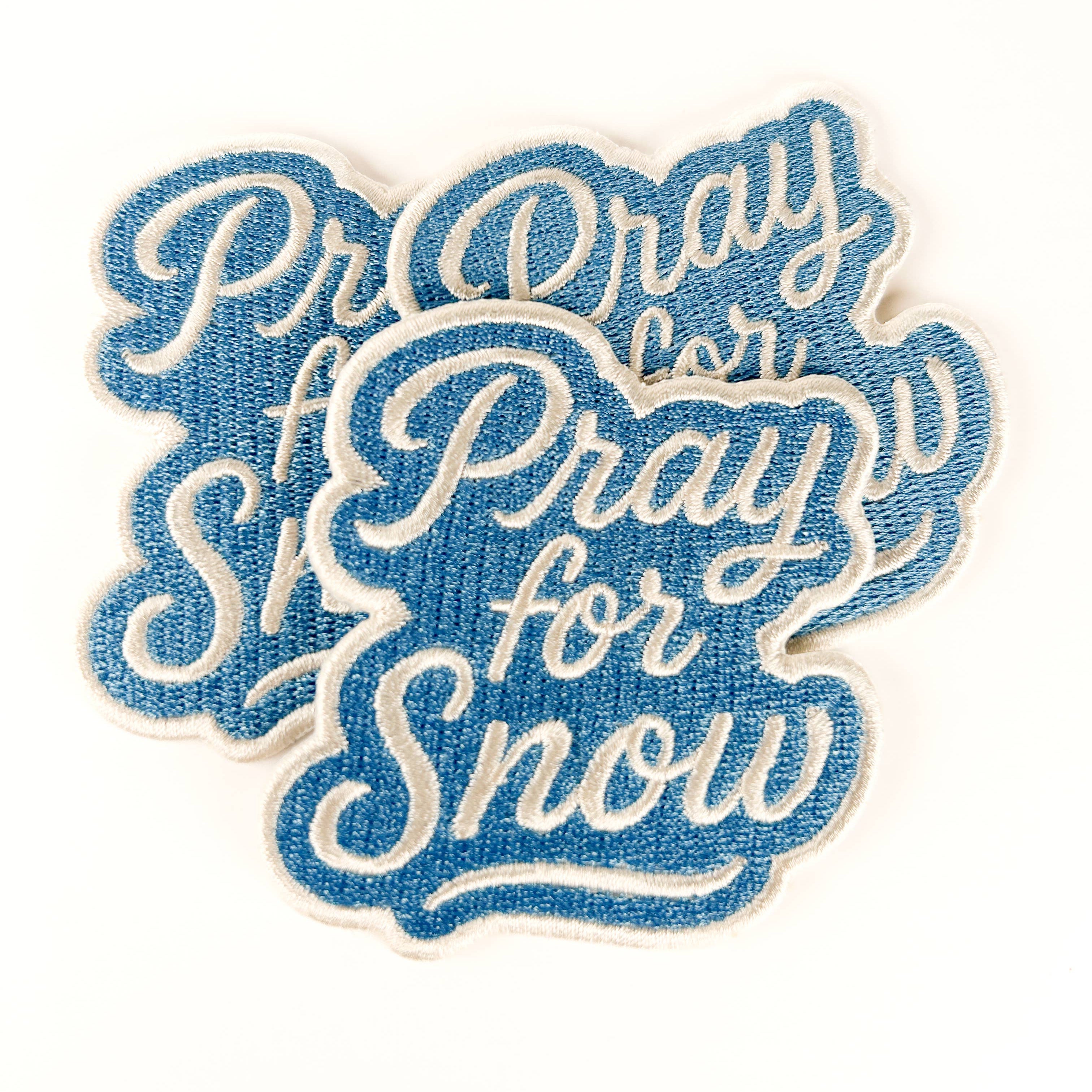Embroidered patch with 'Pray for Snow' text on a white background