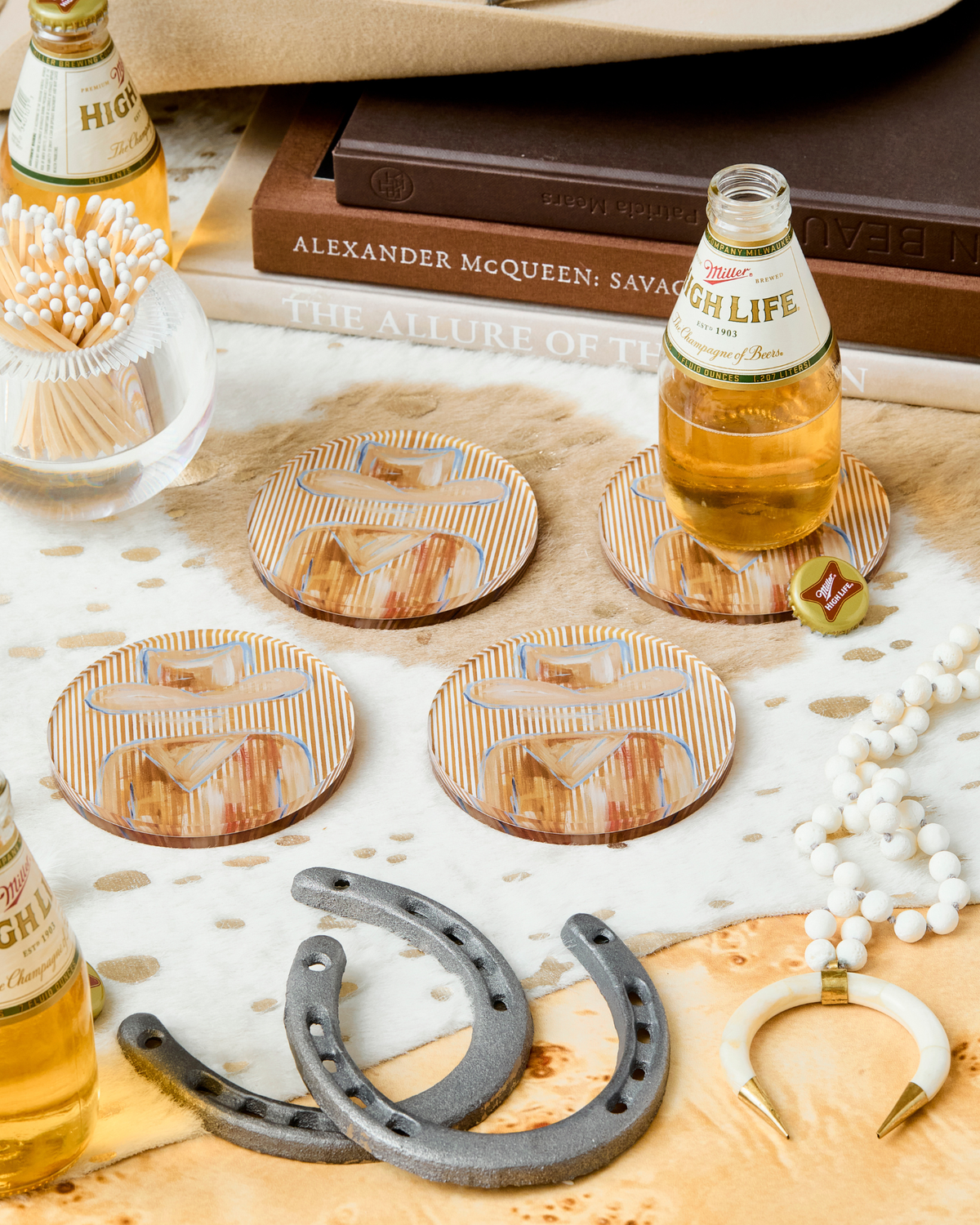 Coasters with a horse design on a table with High Life beer bottles and a horseshoe.