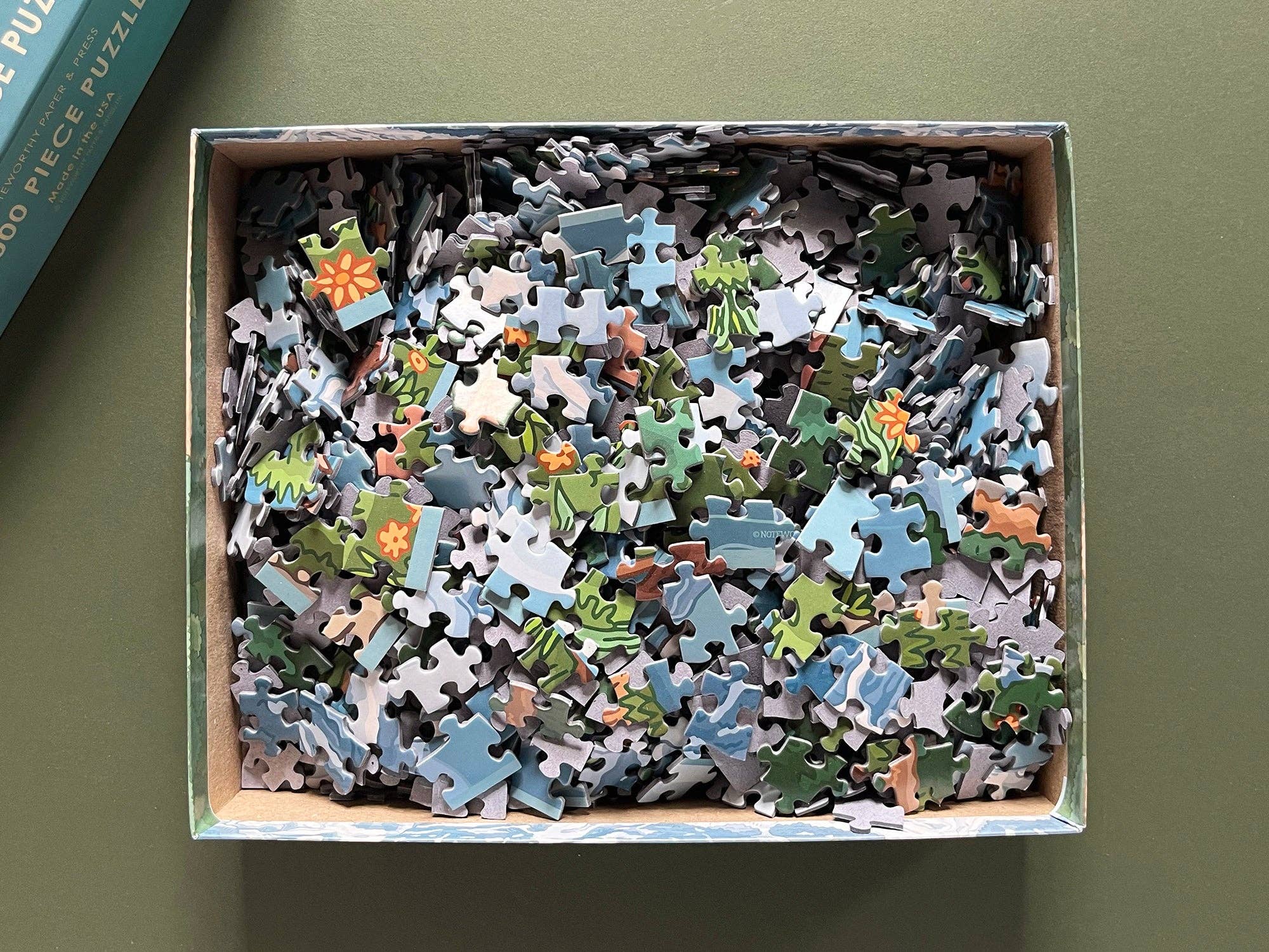 Box of puzzle pieces on a green background