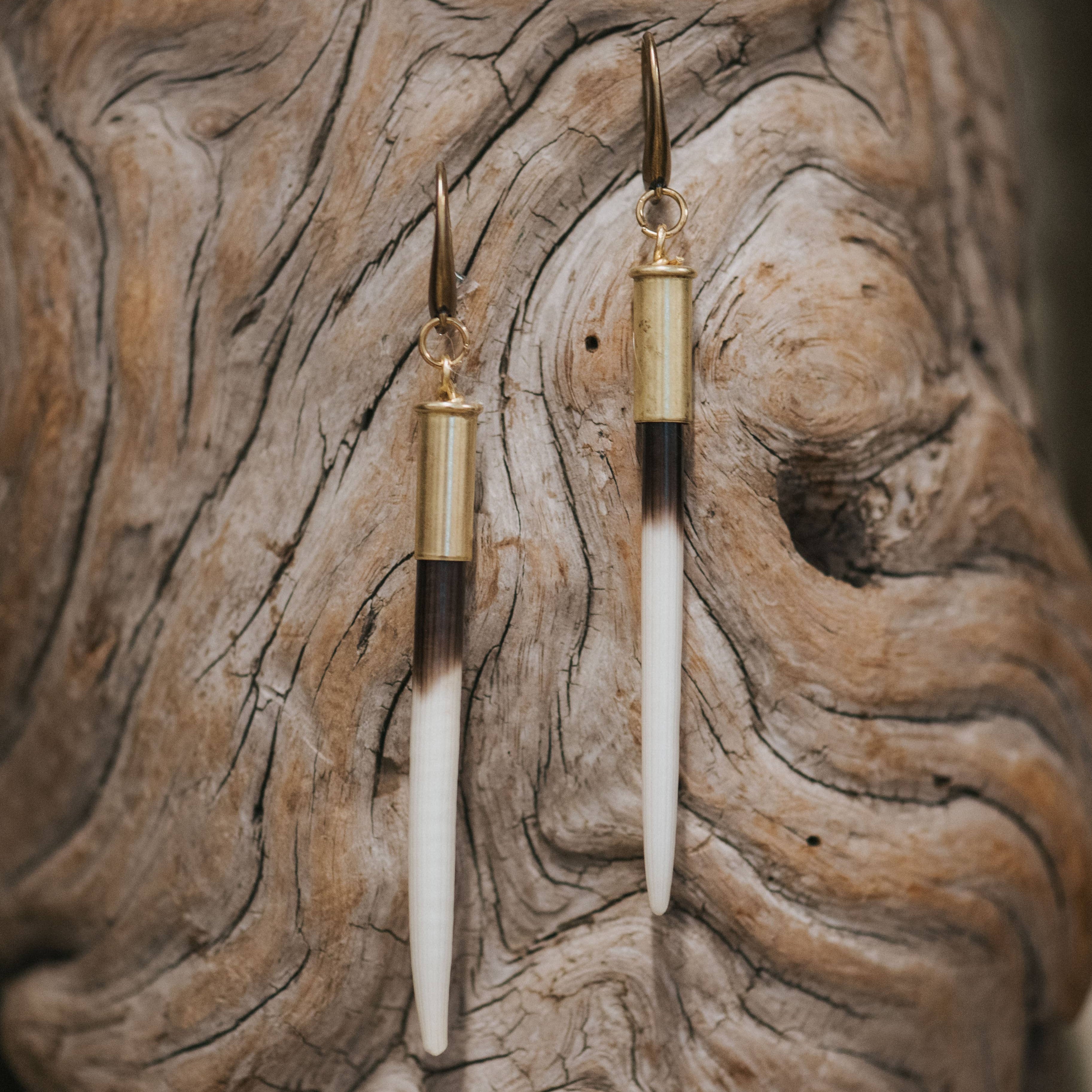 Two gold and white pen-like objects on a textured wooden surface