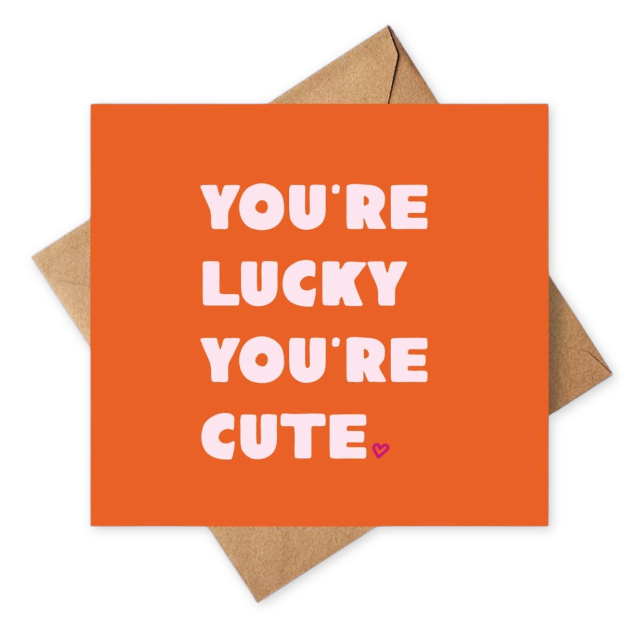 Orange card with 'You're lucky you're cute' text and a heart symbol, placed on a brown envelope.