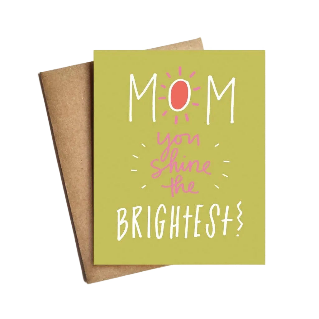 A greeting card with a green background and the text 'Mom You must be the brightest' in a circular pink and white design, accompanied by a kraft envelope.