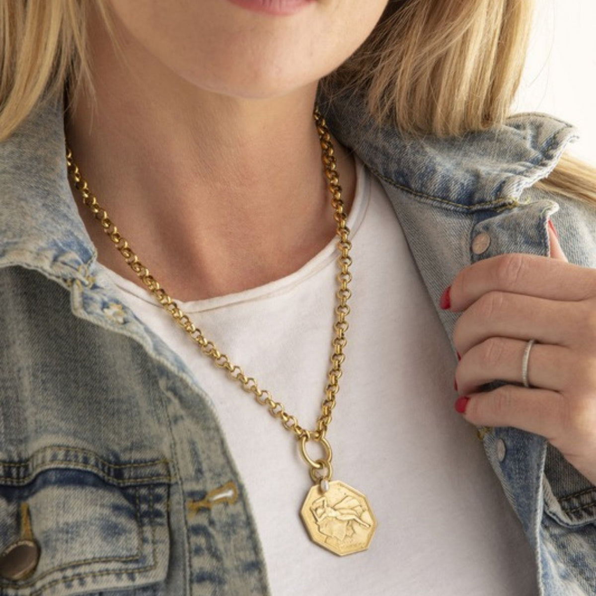 Woman in a denim jacket and white tee wearing a gold rolo chain necklace with an octagonal coin pendant