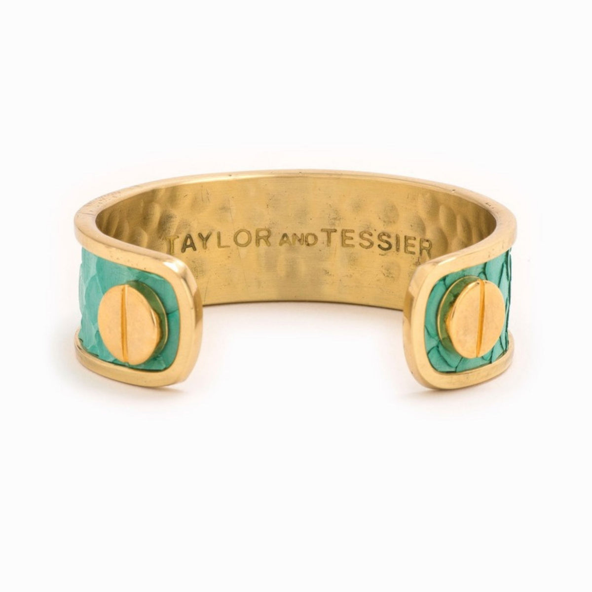 Inside view of a gold cuff with turquoise green leather panels, gold screw heads and engraved logo