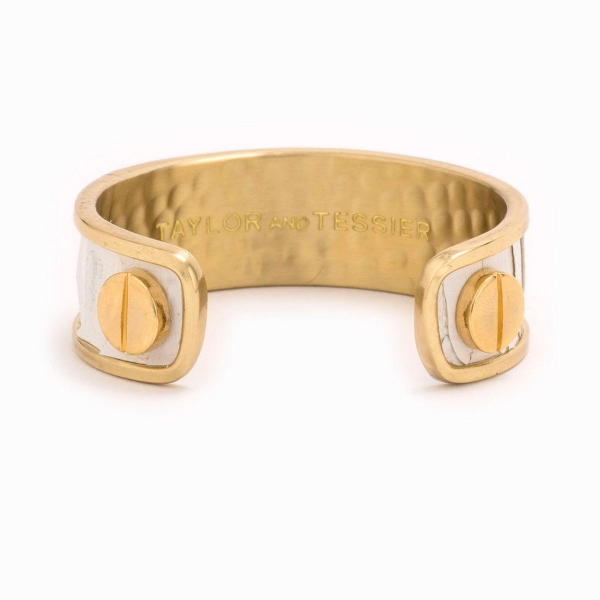 Inside view of a gold cuff with white leather panels, gold screw heads and a hammered interior with logo