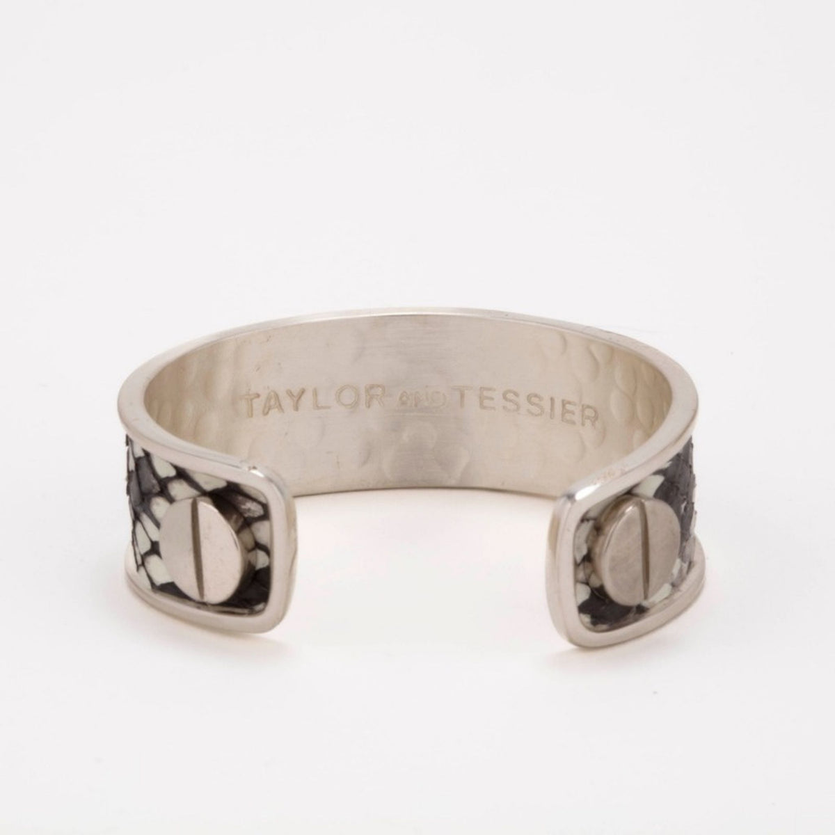 Inside view of a silver cuff with black and white snakeskin-textured leather ends and silver screw heads