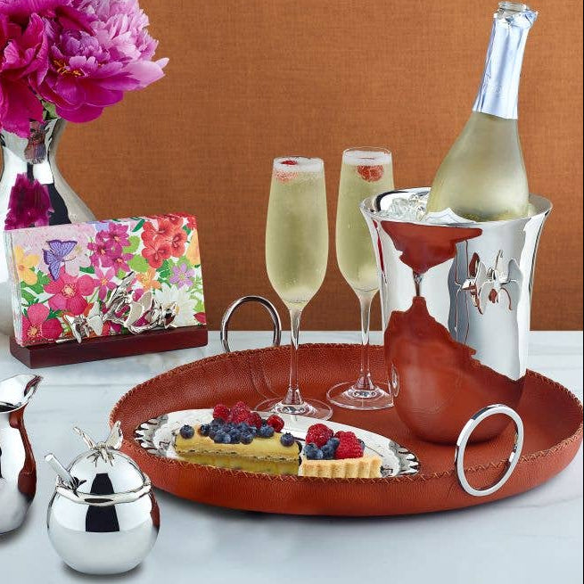 Table setting with champagne, pastries, and flowers on a red tray.