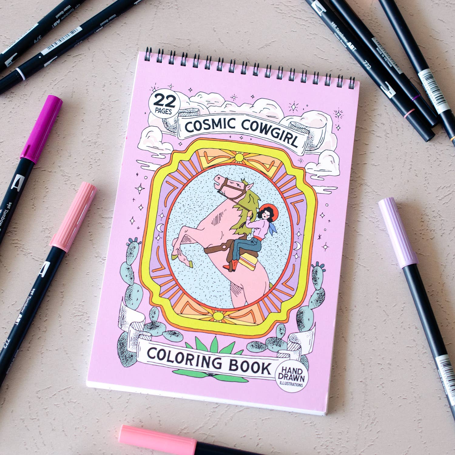Coloring book titled 'Cosmic Cowgirl' with markers on a light surface