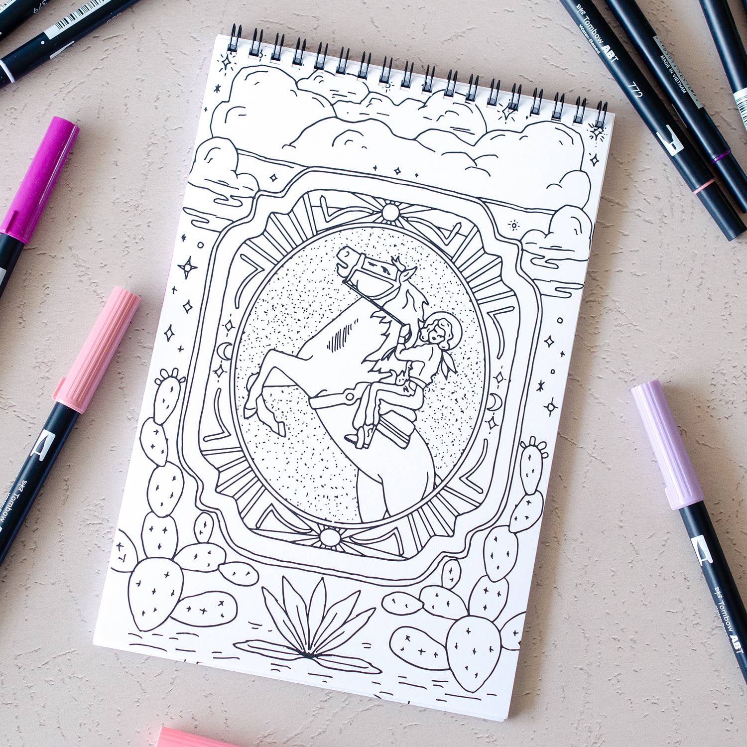 Coloring book page with a horse and star design on a table with markers.