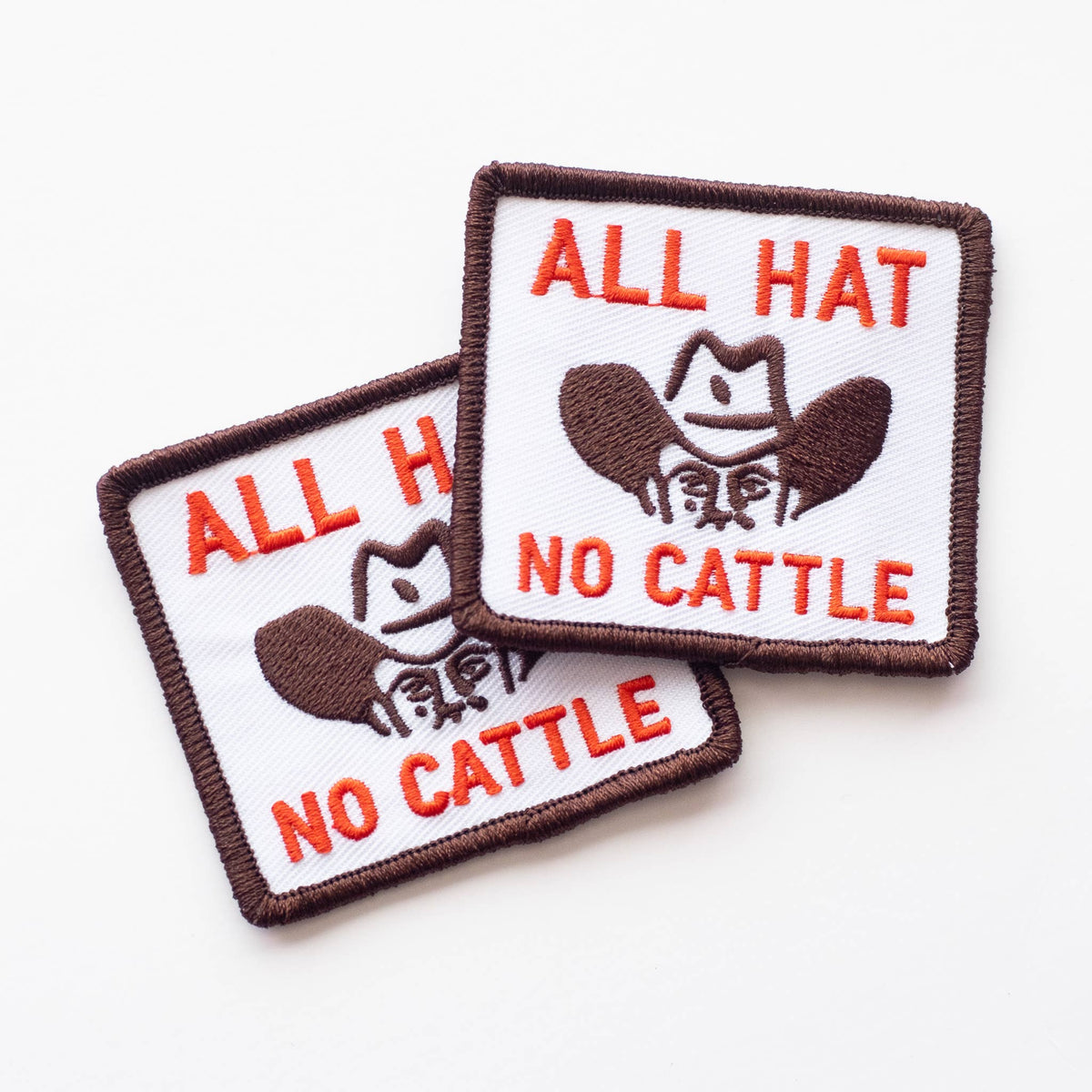 Two patches with 'All Hat No Cattle' text and a cowboy hat graphic on a white background.
