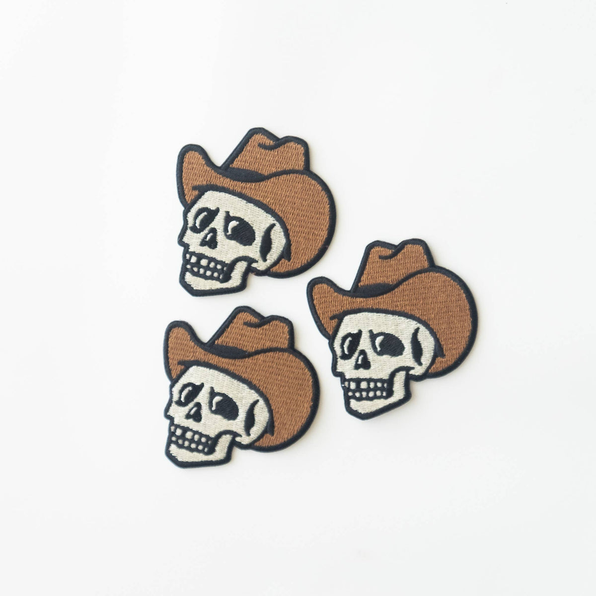 Three skull patches with cowboy hats on a white background.