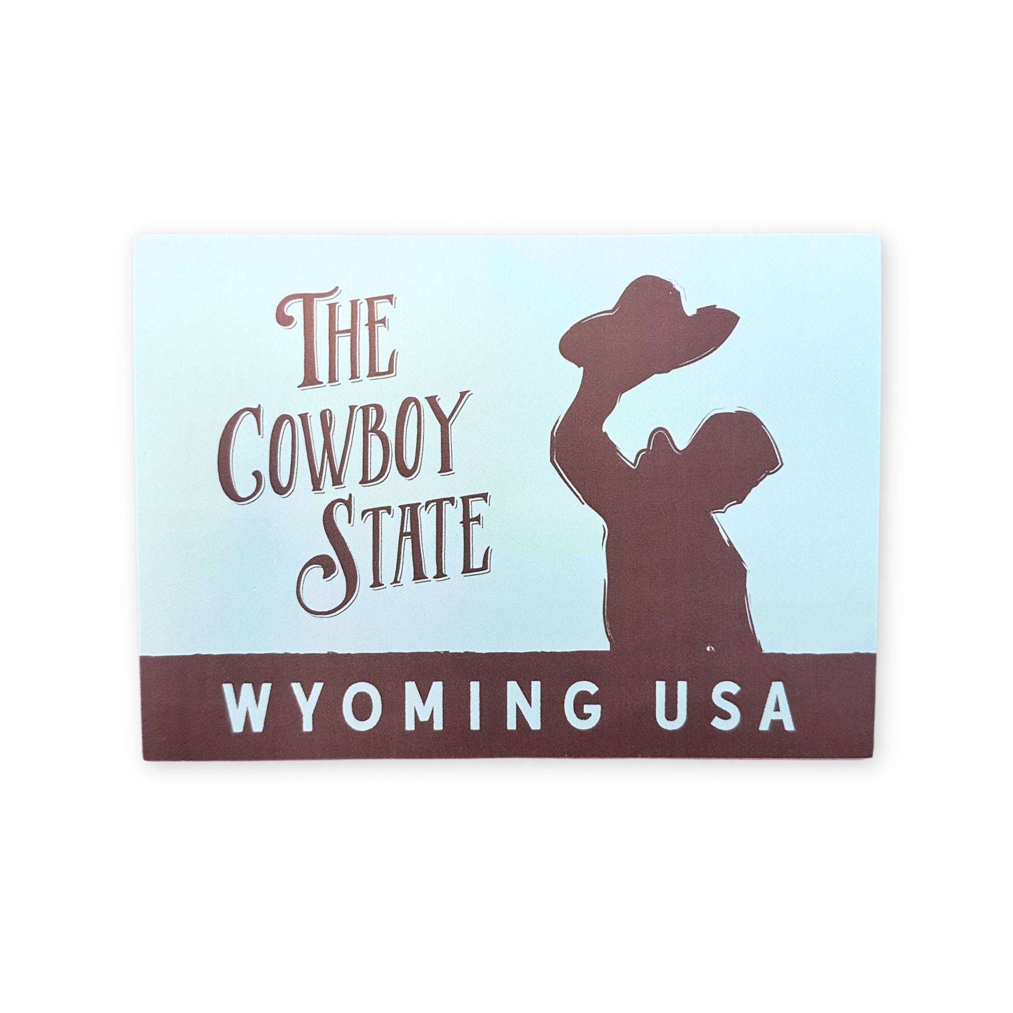 Card with silhouette of a cowboy raising a hat and text 'The Cowboy State Wyoming USA' on a light blue background.