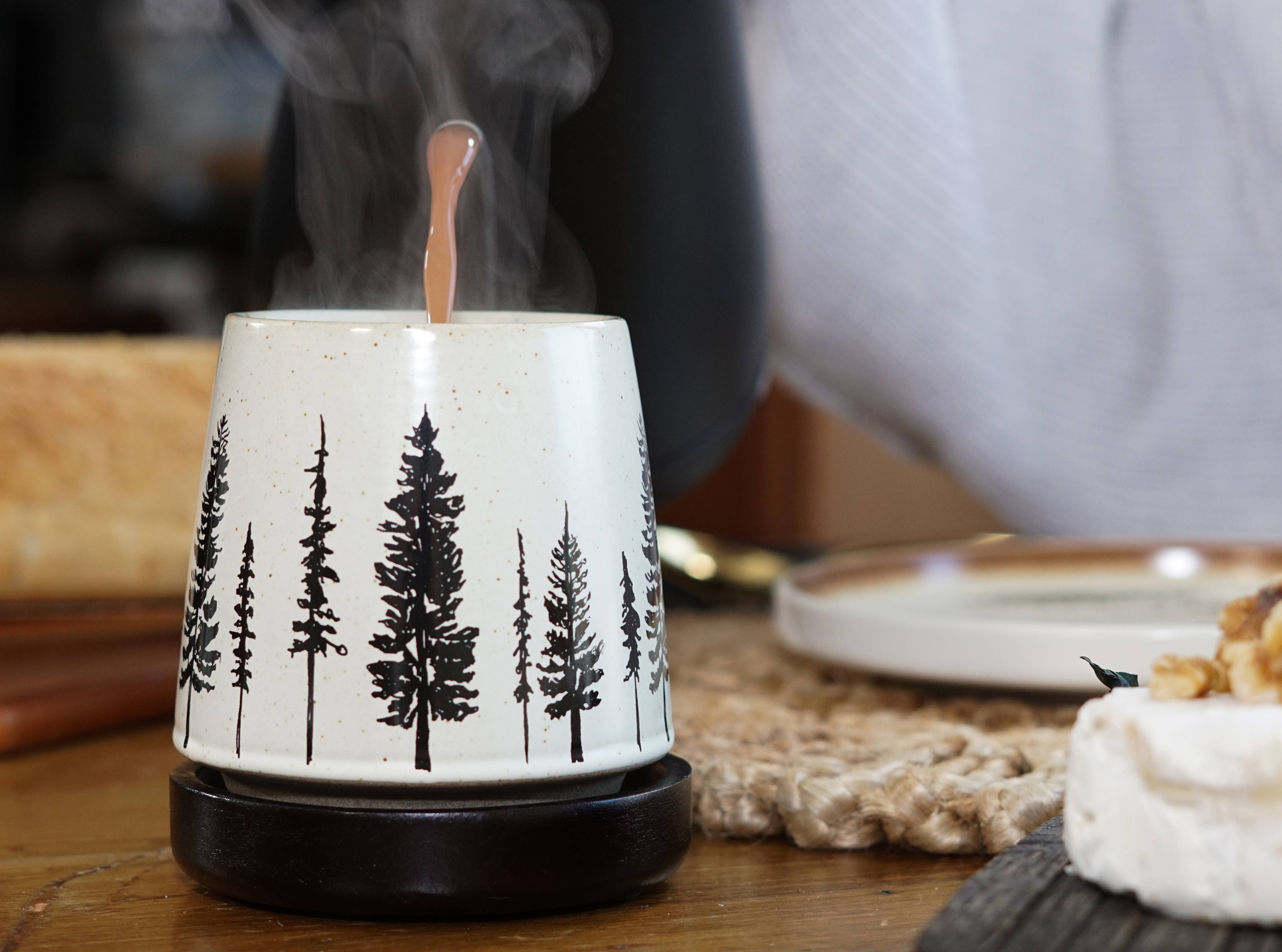 Ceramic Mug with tree designs on a wooden table.