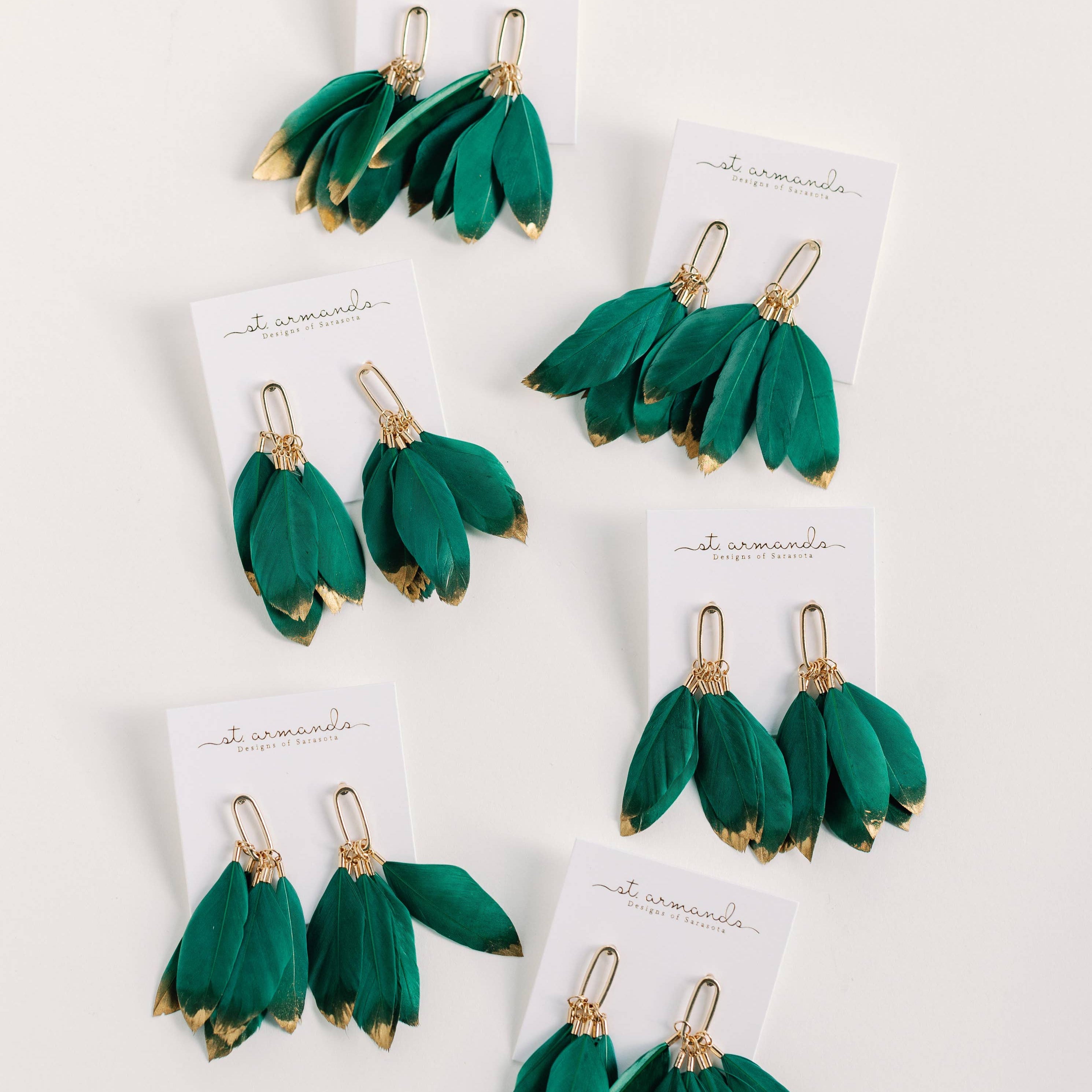 Set of green feather earrings on white cards with a white background