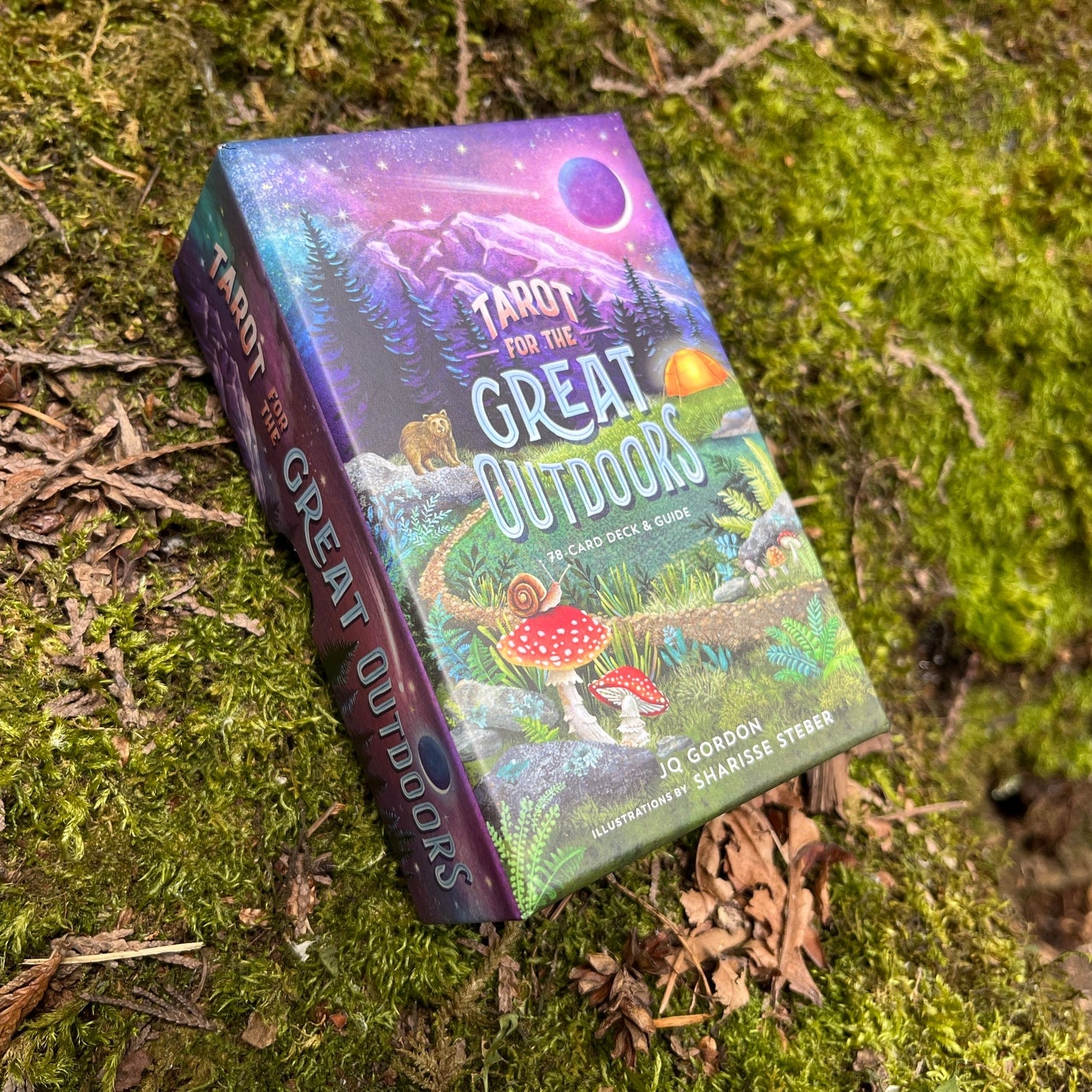 Colorful book titled 'Tarot for the Great Outdoors' on a mossy surface