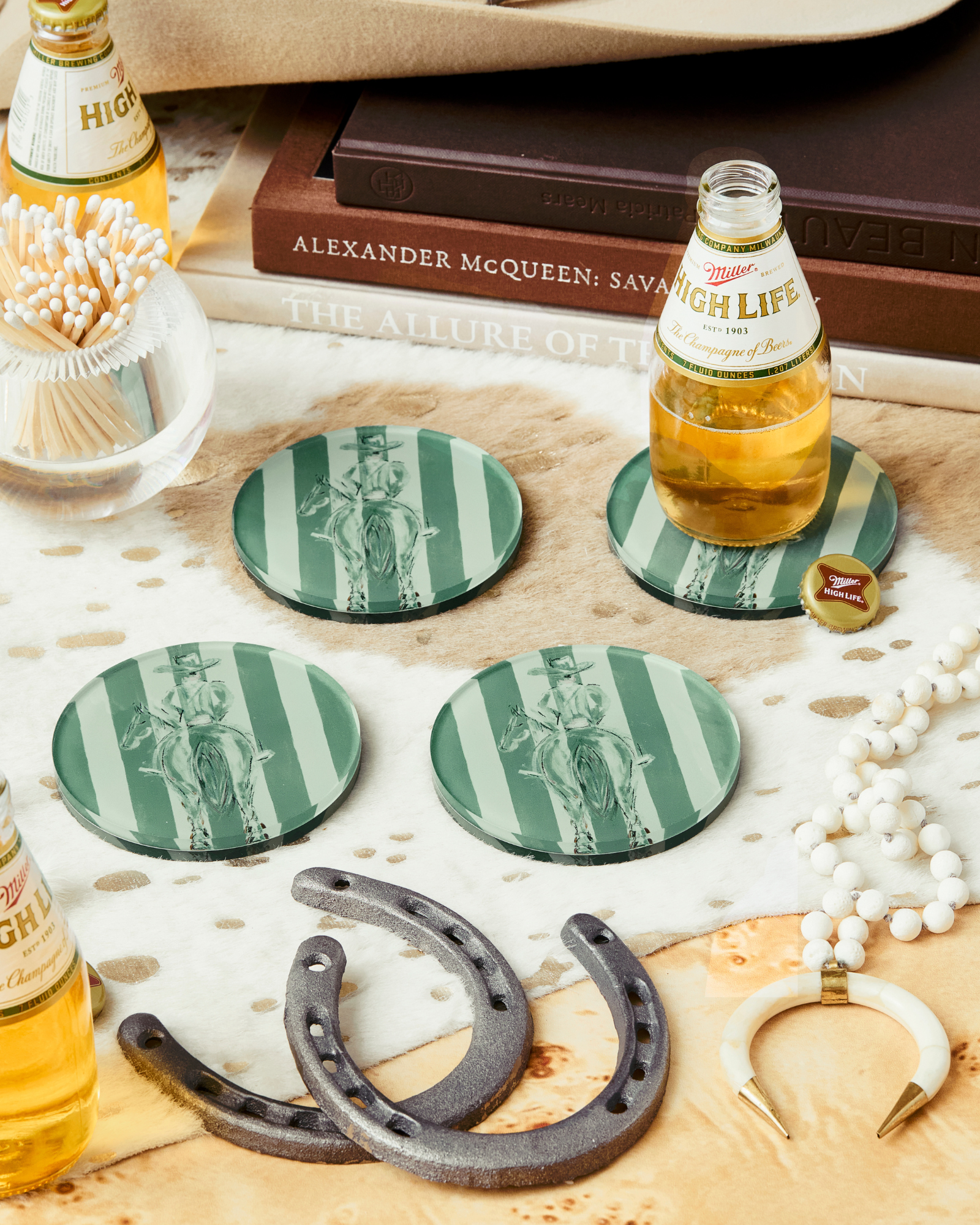 Coasters with green and white designs, beer bottles, and a horseshoe on a wooden surface.