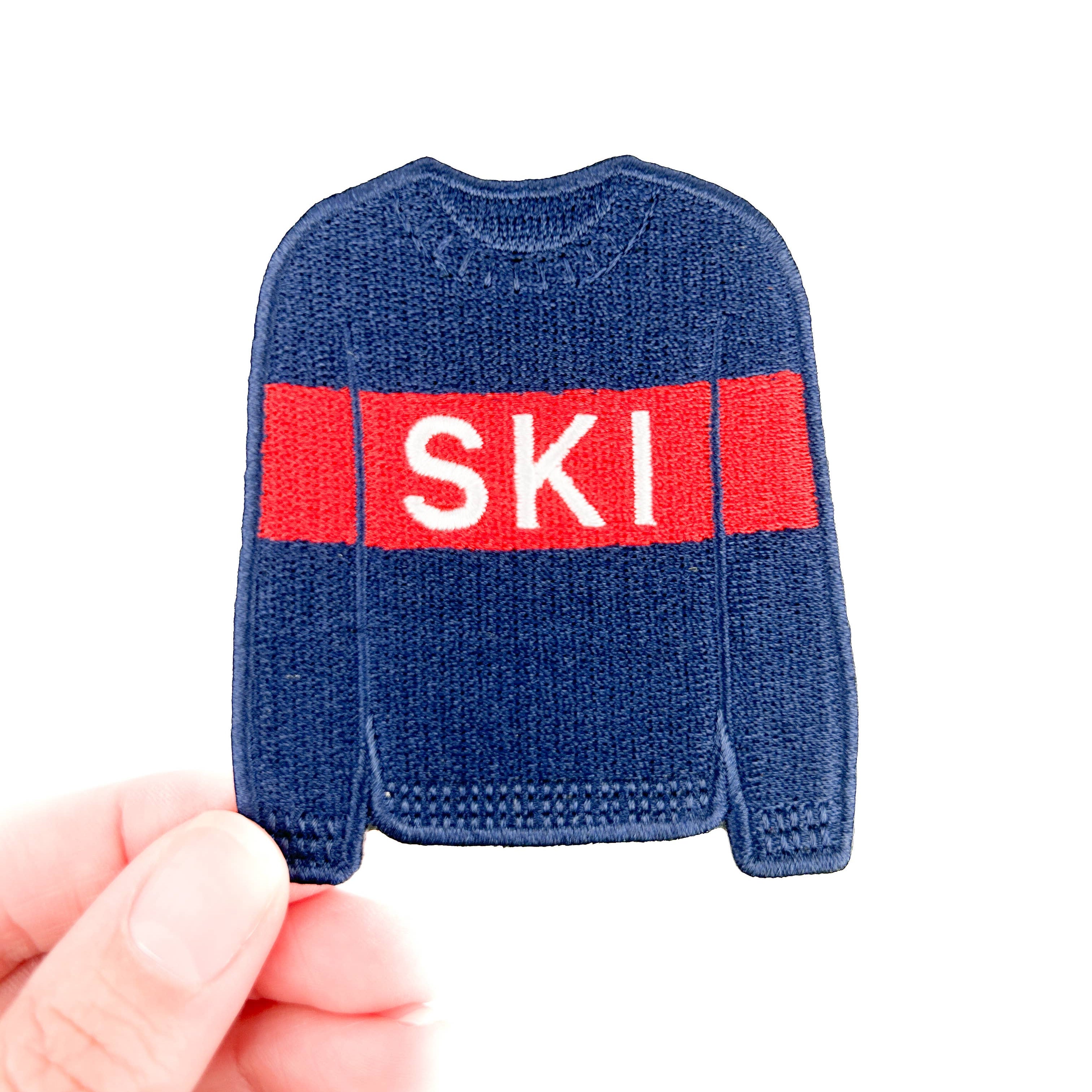 Embroidered iron on patch of a Blue sweater with a red band displaying the word 'SKI'.