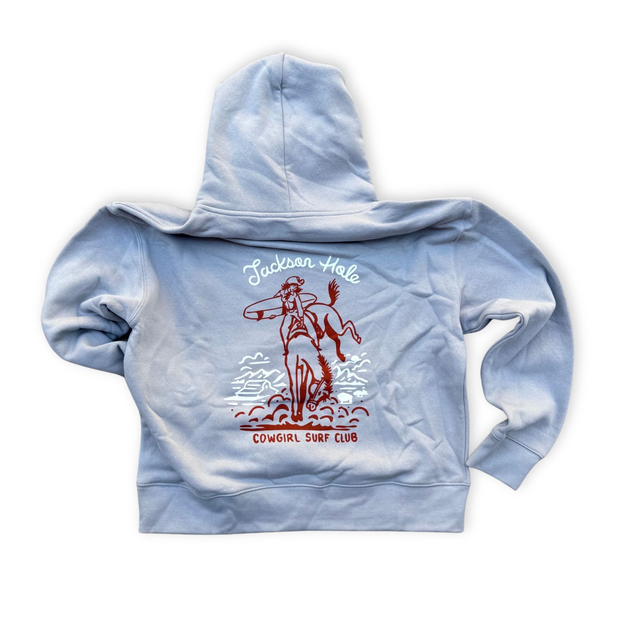 A light blue zip-up hoodie shown from the back, featuring a graphic print of a cowboy riding a bucking horse with the text 'Jackson Hole' and 'Cowgirl Surf Club' in red and white.