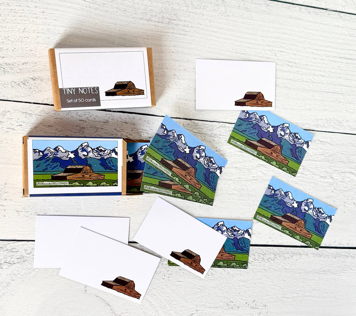 A set of note cards and matching envelopes featuring an illustrated Barn against mountain scenery.