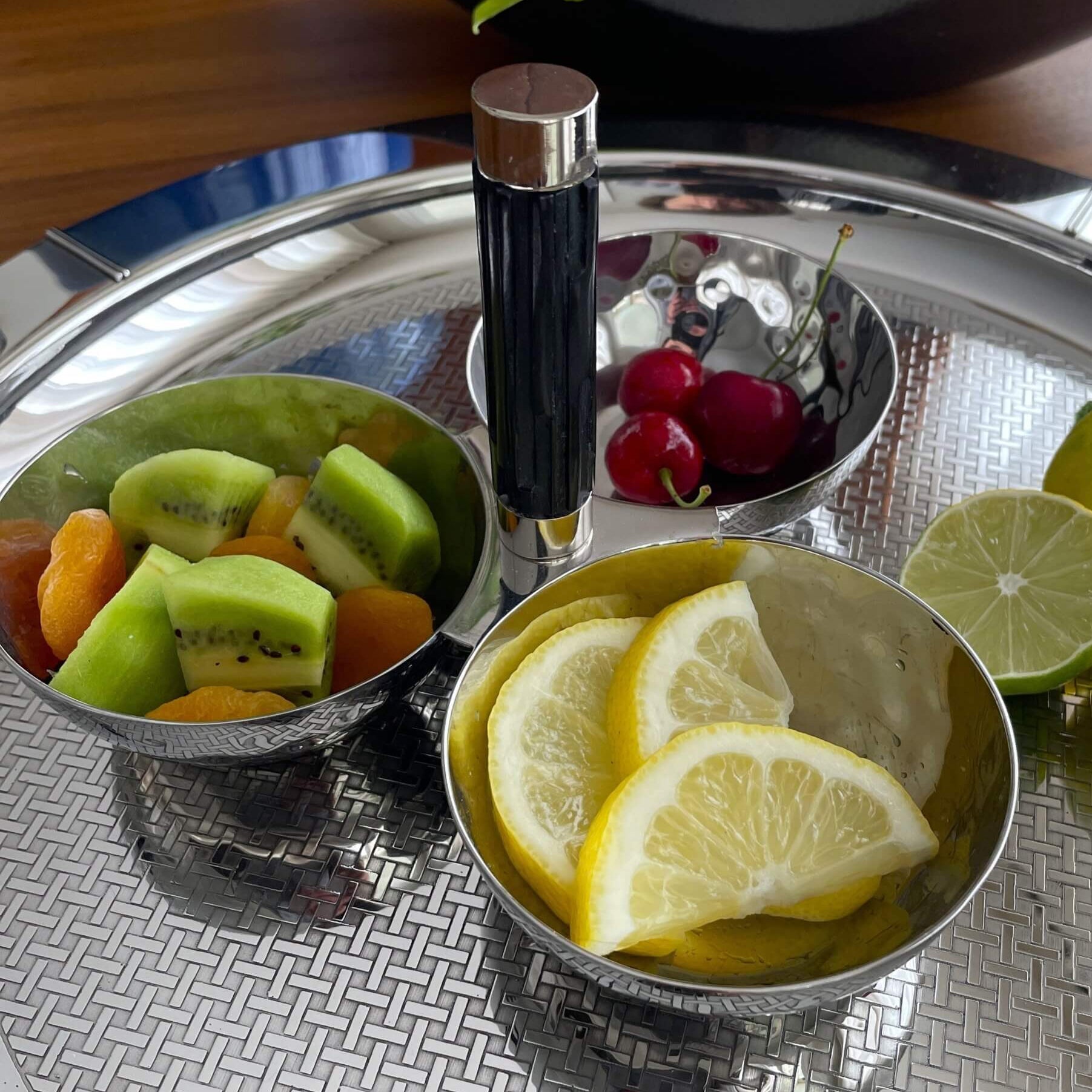 Fruit platter with kiwi, oranges, and lemons on a metallic tray.