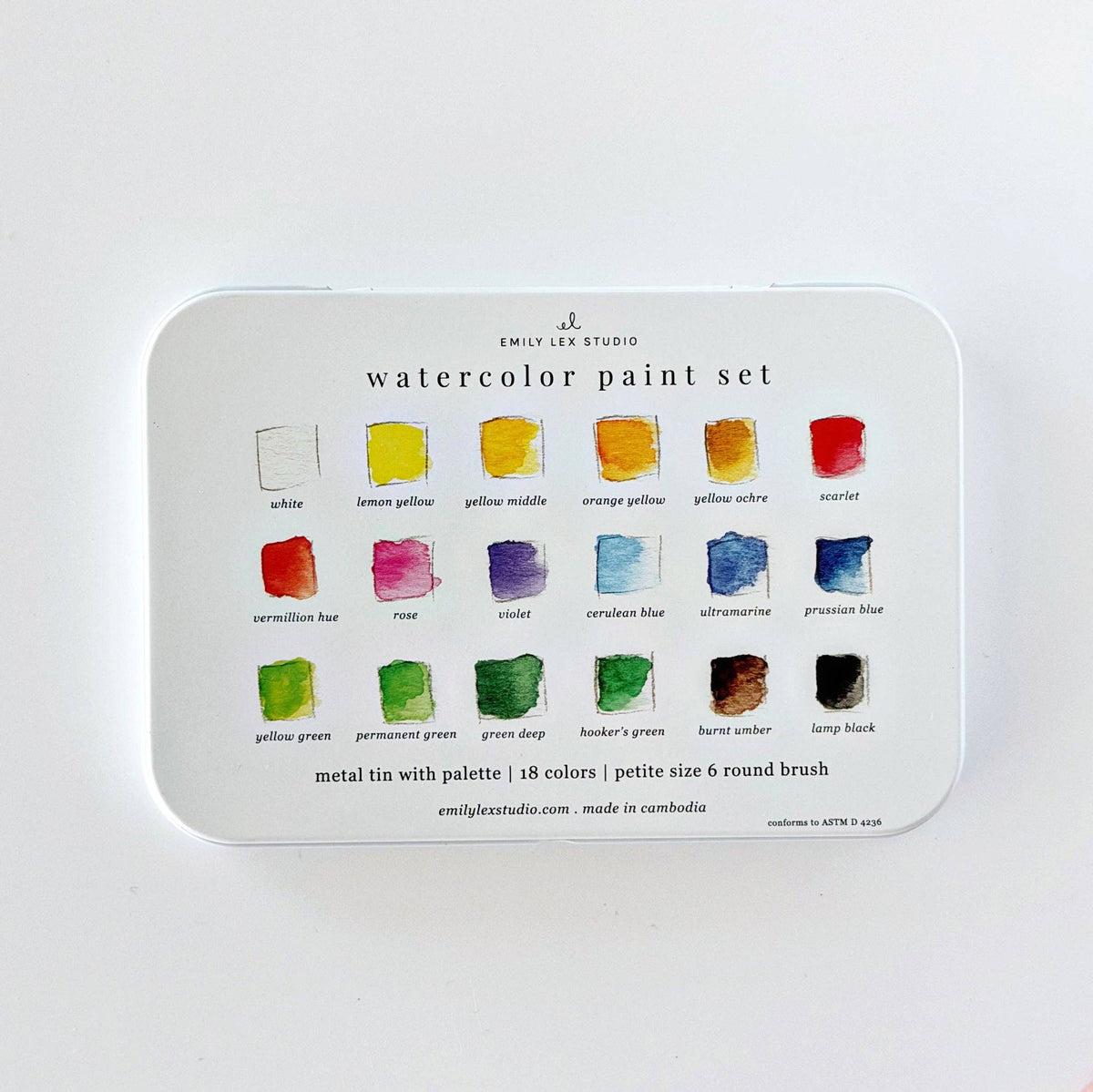 A metal tin watercolor paint set by Emily Lee Studio, showing 18 color wells with labeled watercolor swatches.