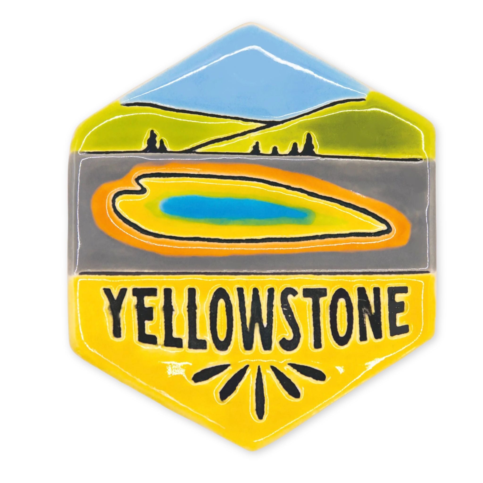 A hexagonal enamel magnet featuring a Yellowstone landscape design with a blue mountain, green hills, a yellow-orange lake, and the word 'YELLOWSTONE' in black on a yellow background.