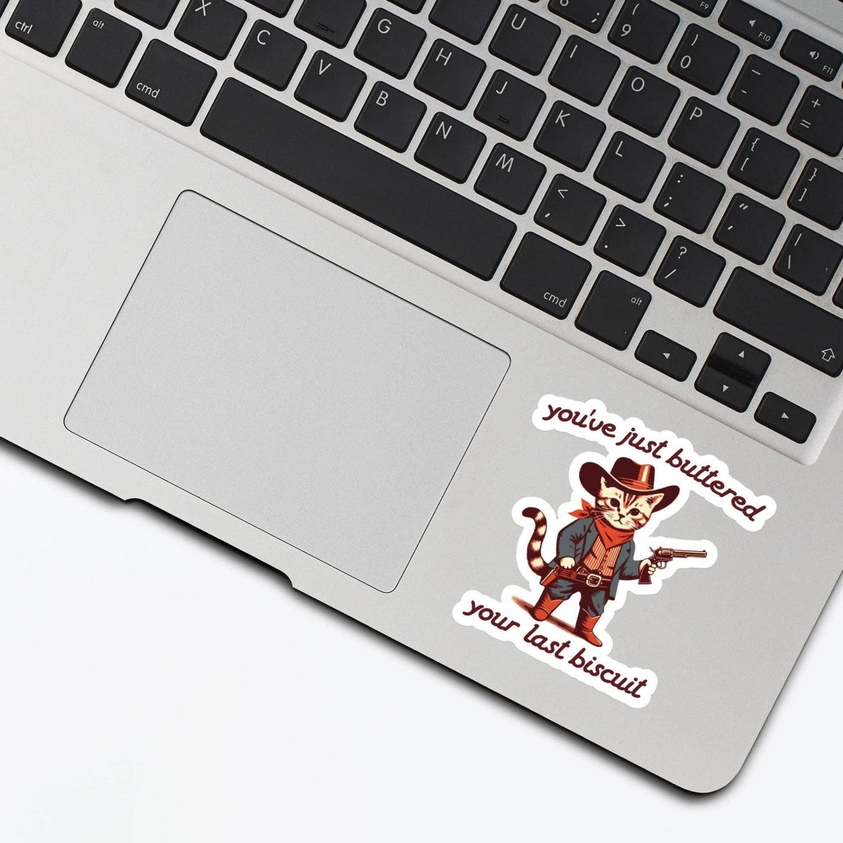 You've Just Buttered Your Last Biscuit Sticker on a laptop trackpad beside the keyboard, glossy vinyl by Sticker Horse
