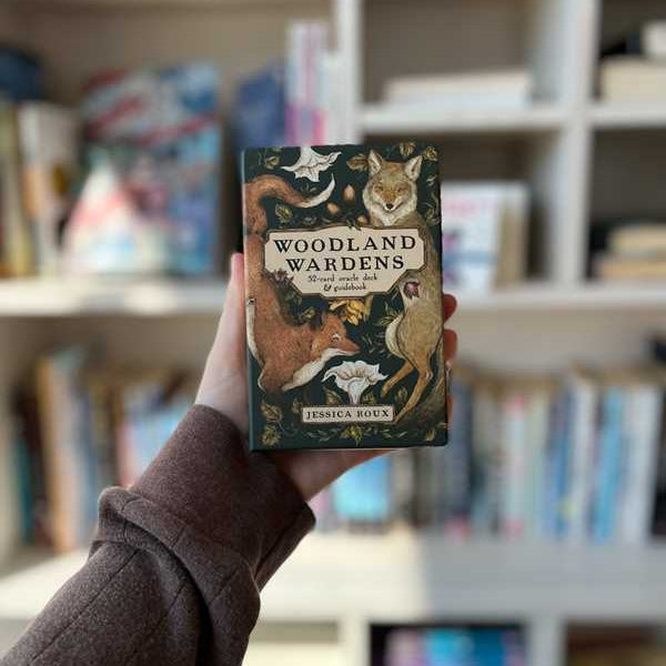 Book titled 'Woodland Wardens' held in front of a bookshelf.