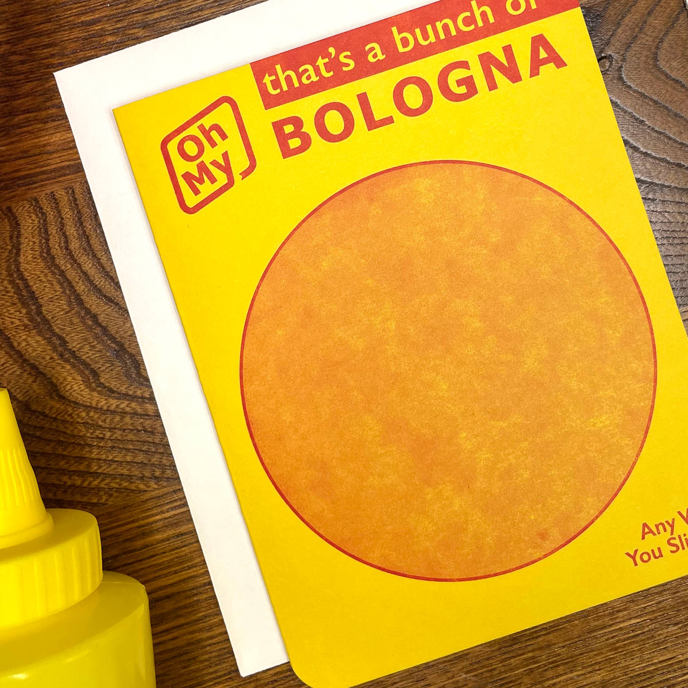 Packaging of 'Oh My Bologna' on a wooden surface with a mustard bottle.