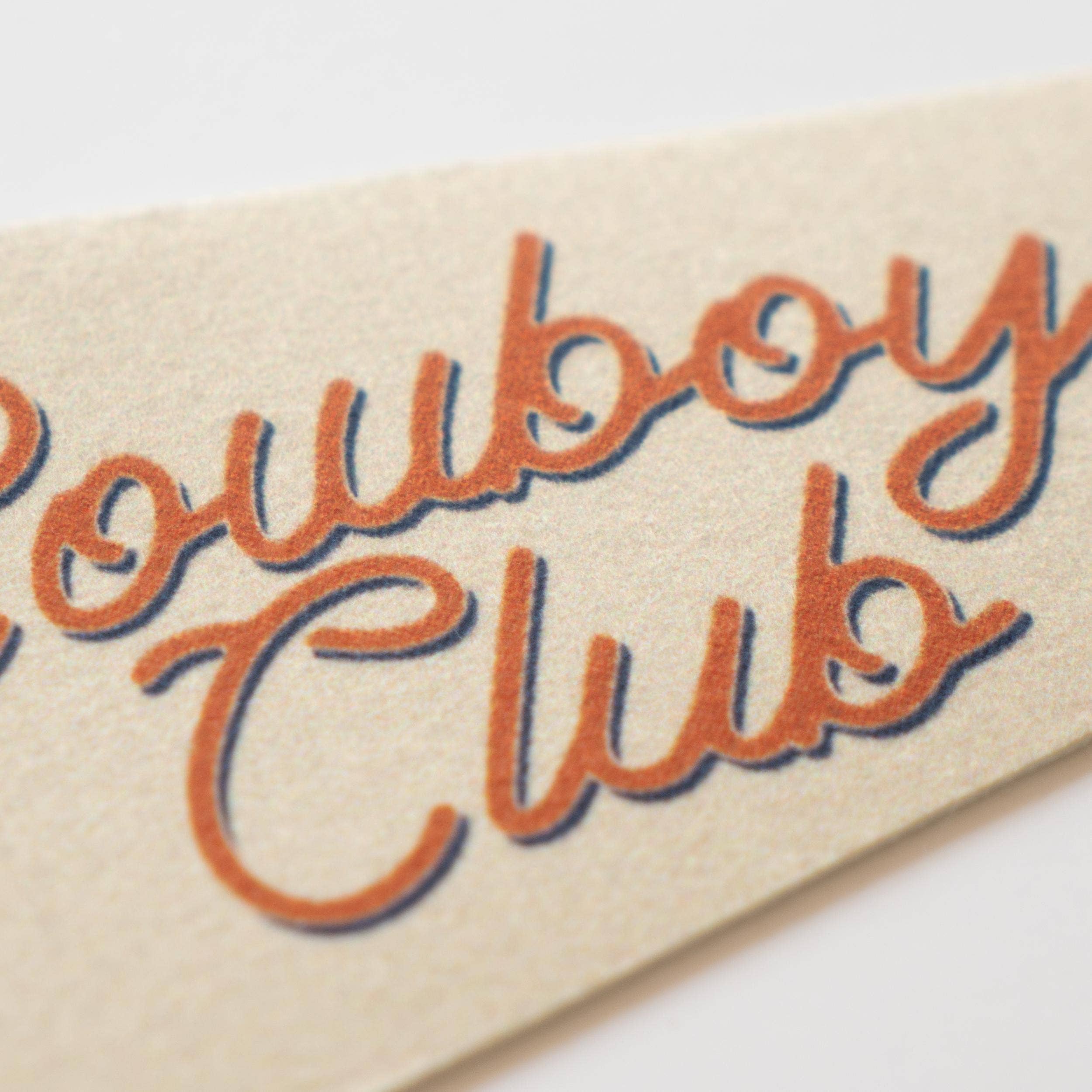 Beige fabric with 'Cowboy Club' embroidery on a white background