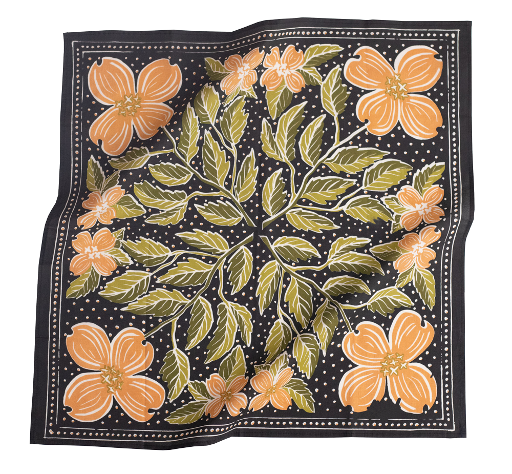 A bandana with a black background featuring peach and green dogwood flowers, and dotted lines across the border.
