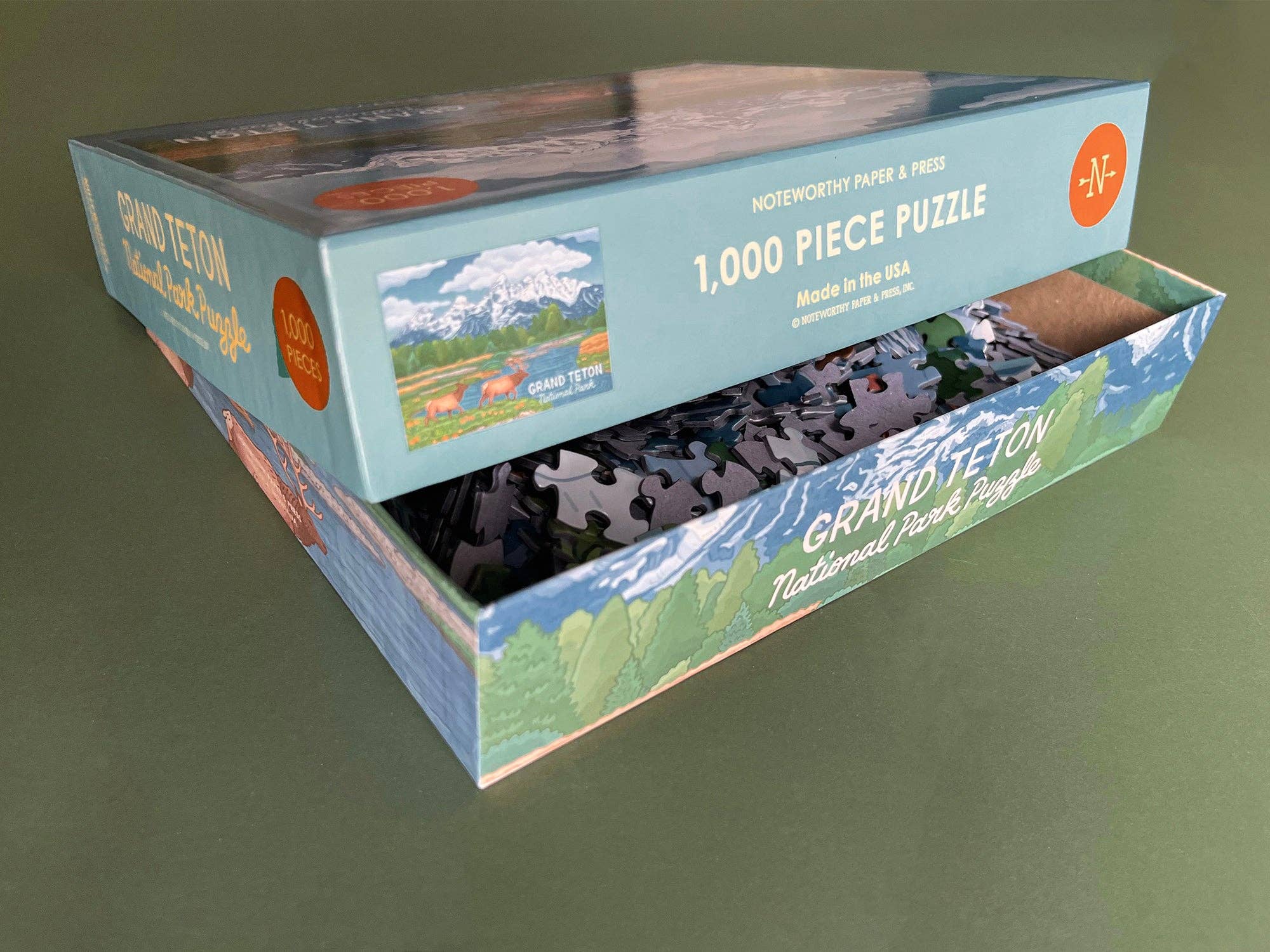 Jigsaw puzzle packaging with mountain scene design on a green background