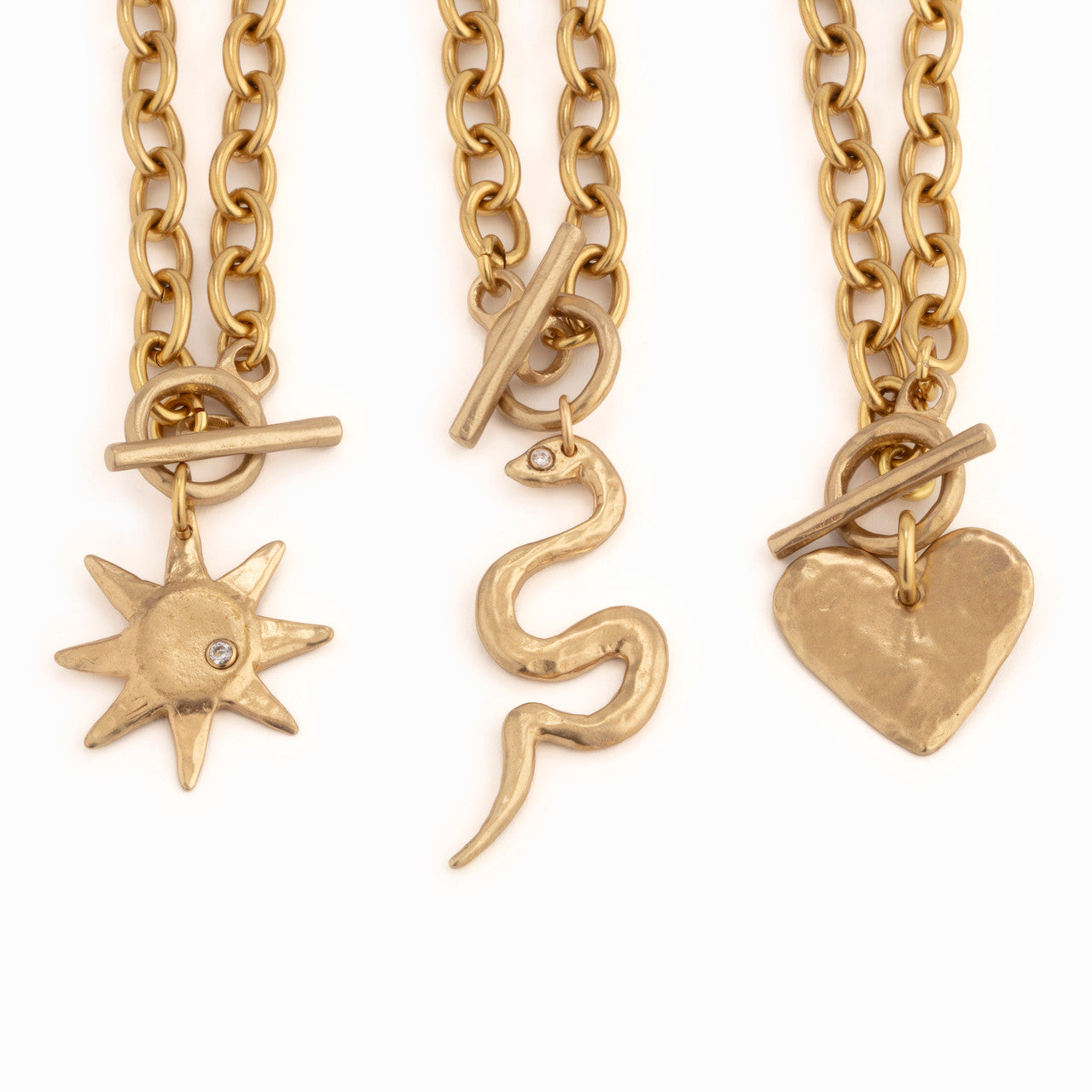 Three gold necklaces with unique pendants on a white background